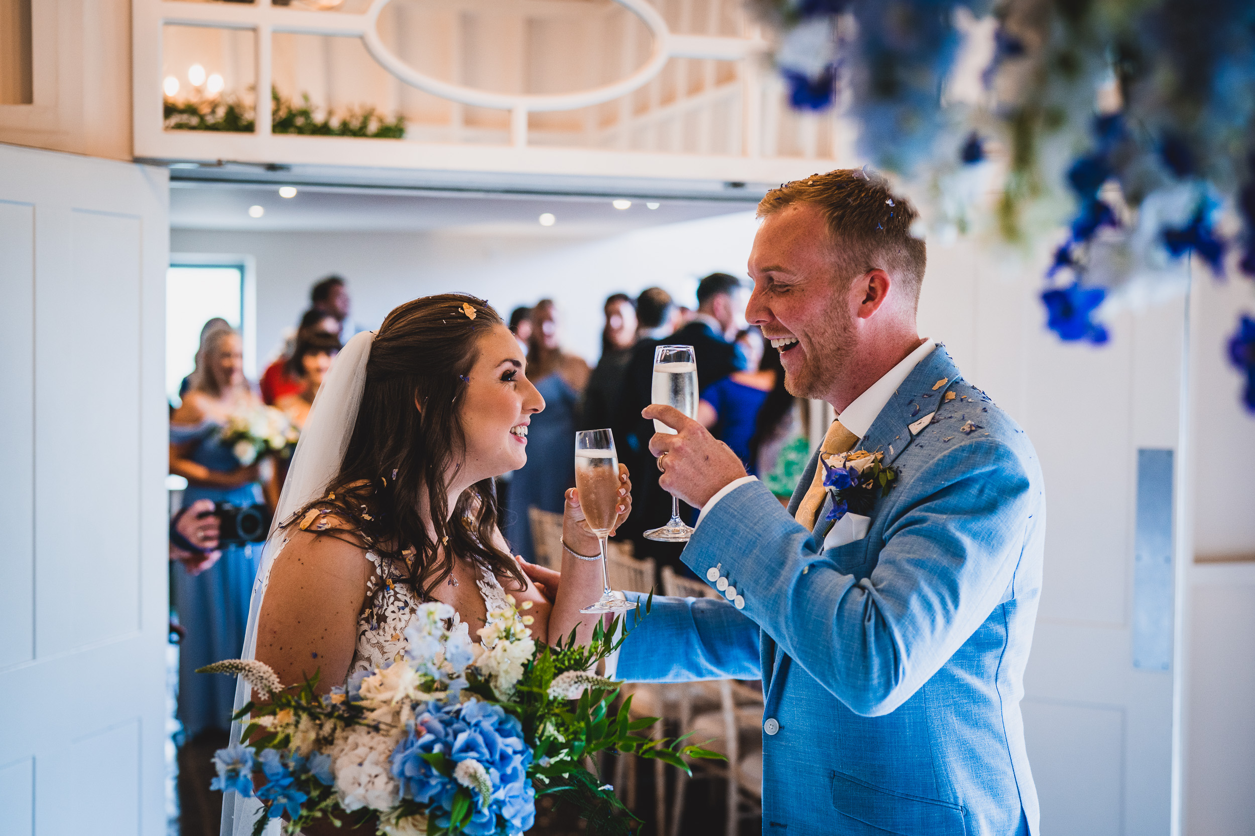 A wedding photographer captures a bride and groom toasting champagne at their wedding ceremony.