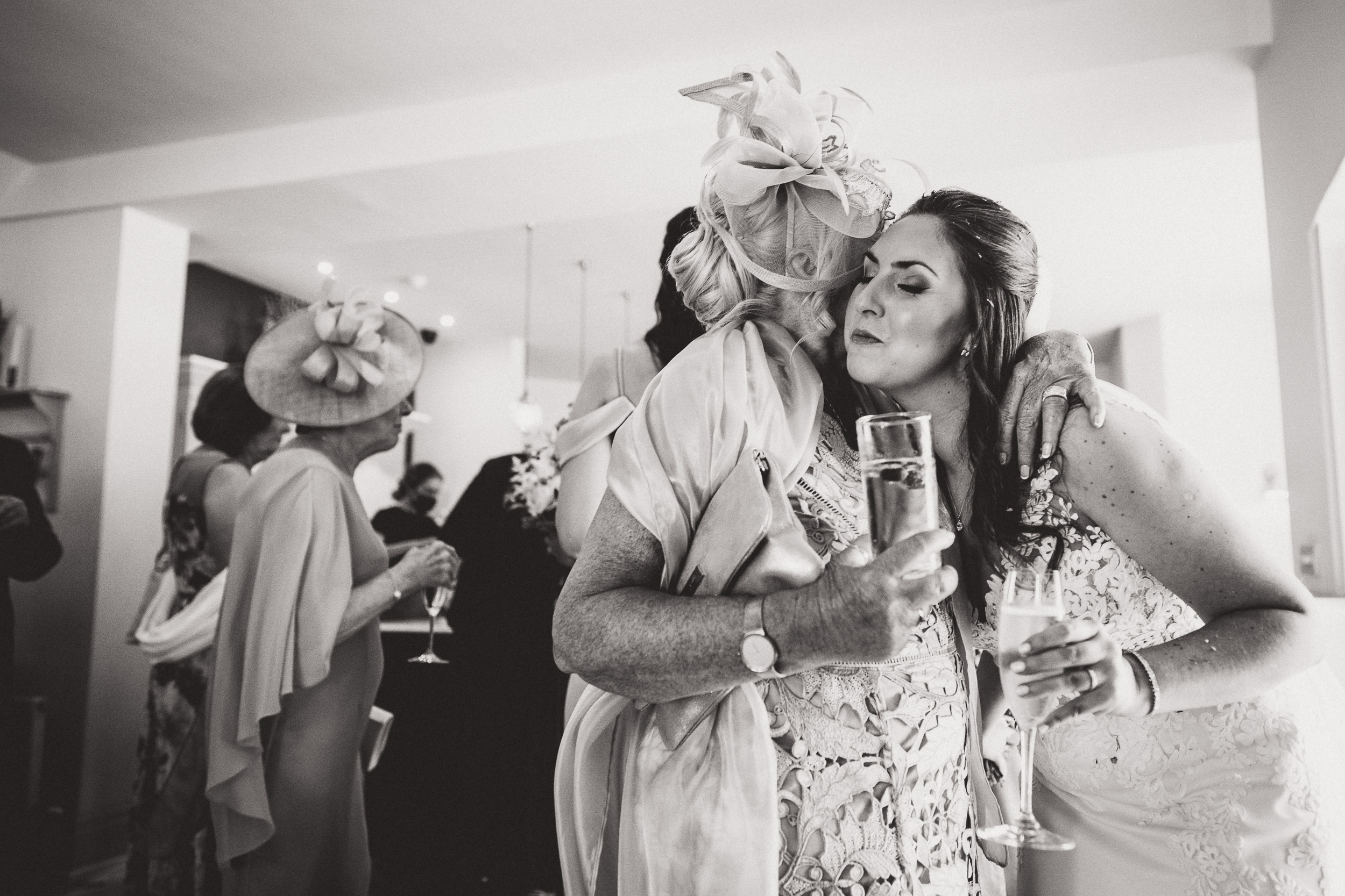 At a wedding, a woman passionately kisses another woman while the groom overlooks the touching moment.