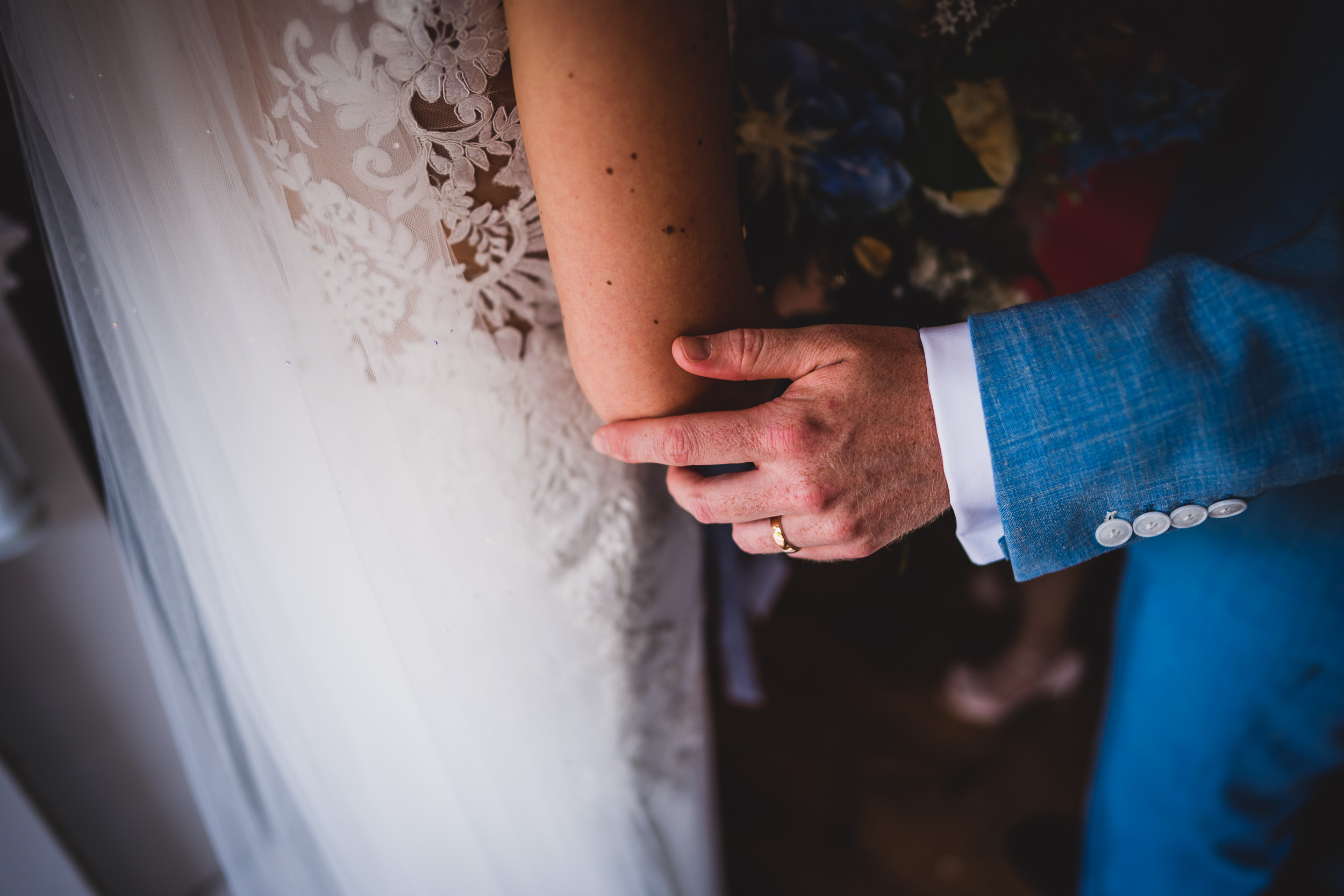 A wedding photo of the bride and groom intimately holding hands.