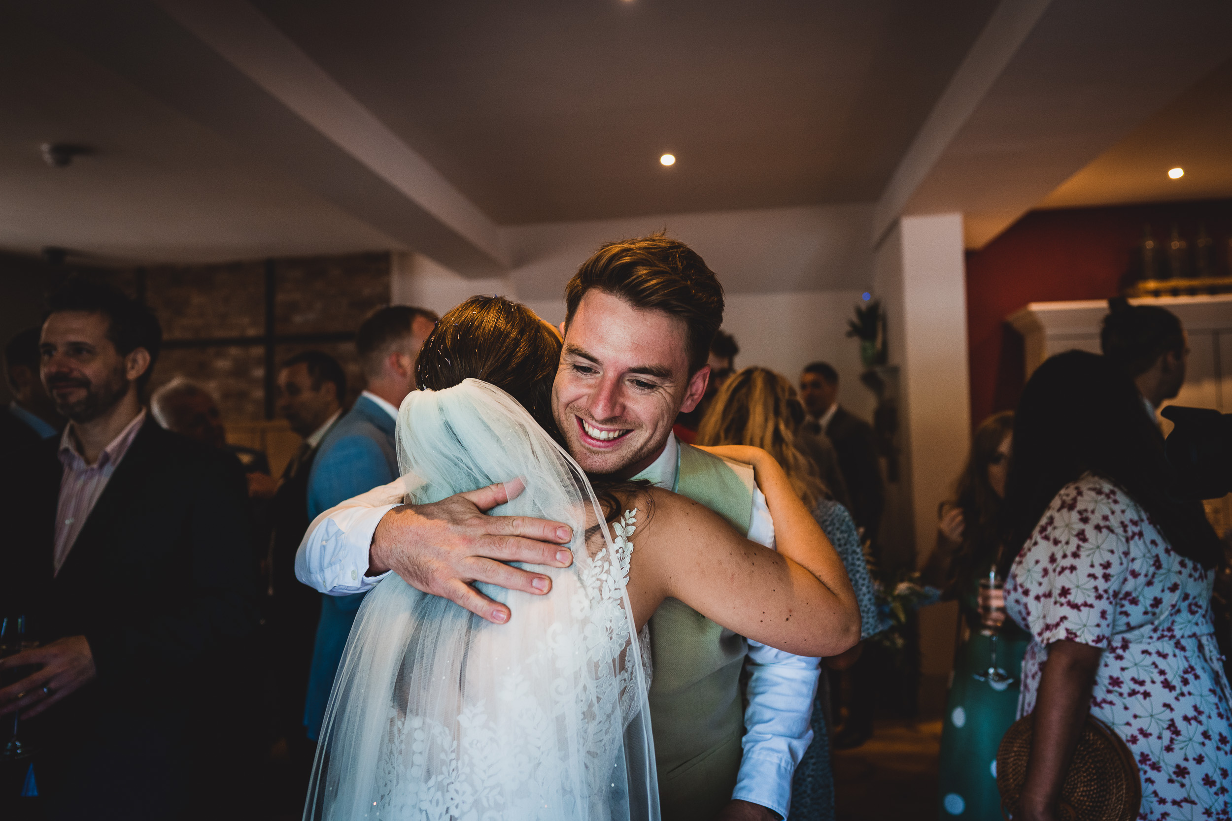 A wedding photographer captures a joyful embrace between the groom and bride at their reception.