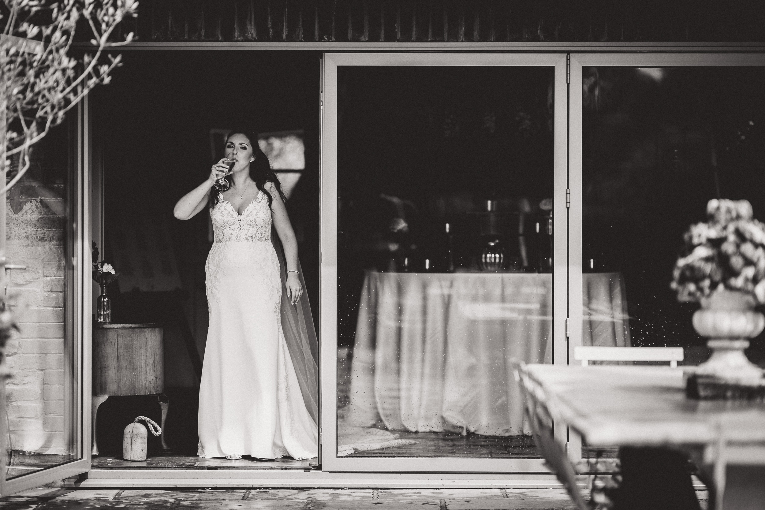 A bride and groom posing together for a wedding photo in front of a glass door.