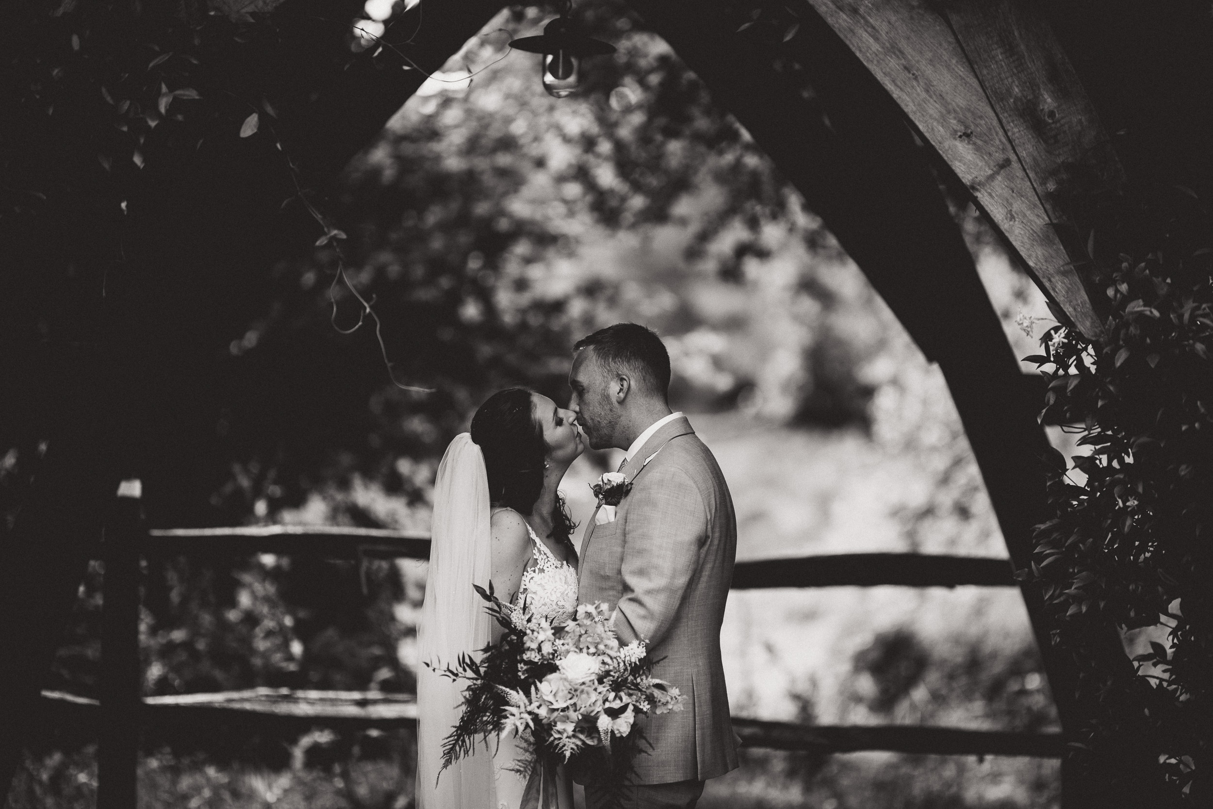 A black and white photo capturing a bride and groom's romantic kiss, taken by a wedding photographer.