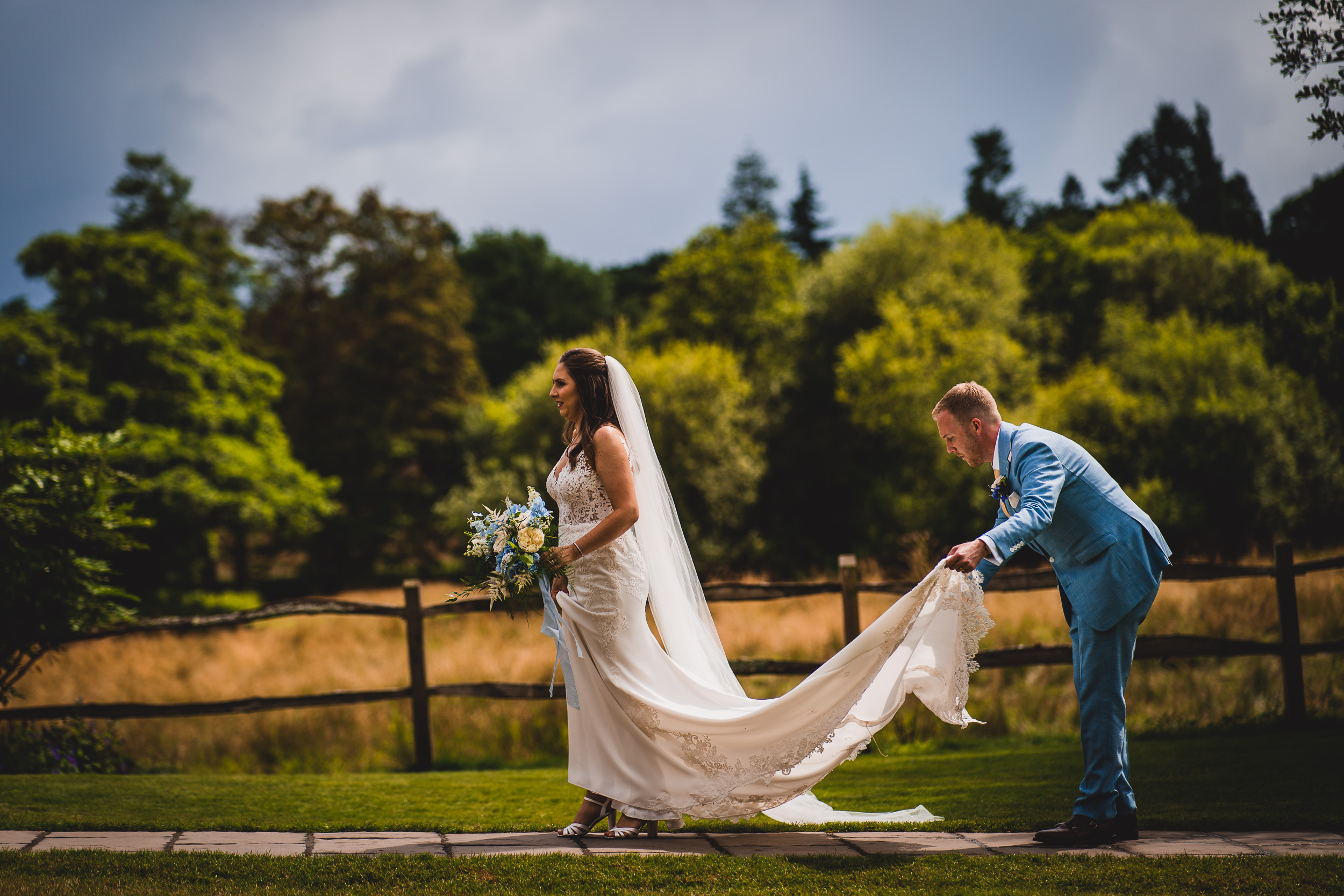 A wedding couple strolling through a picturesque field adorned in their wedding attire.