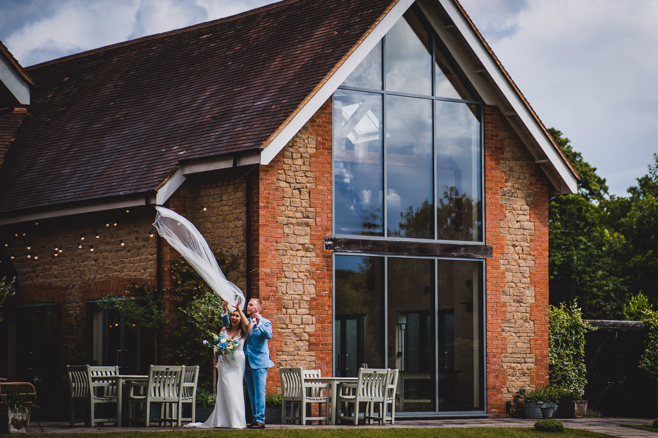 A bride and groom posing for a wedding photo in front of a brick building.