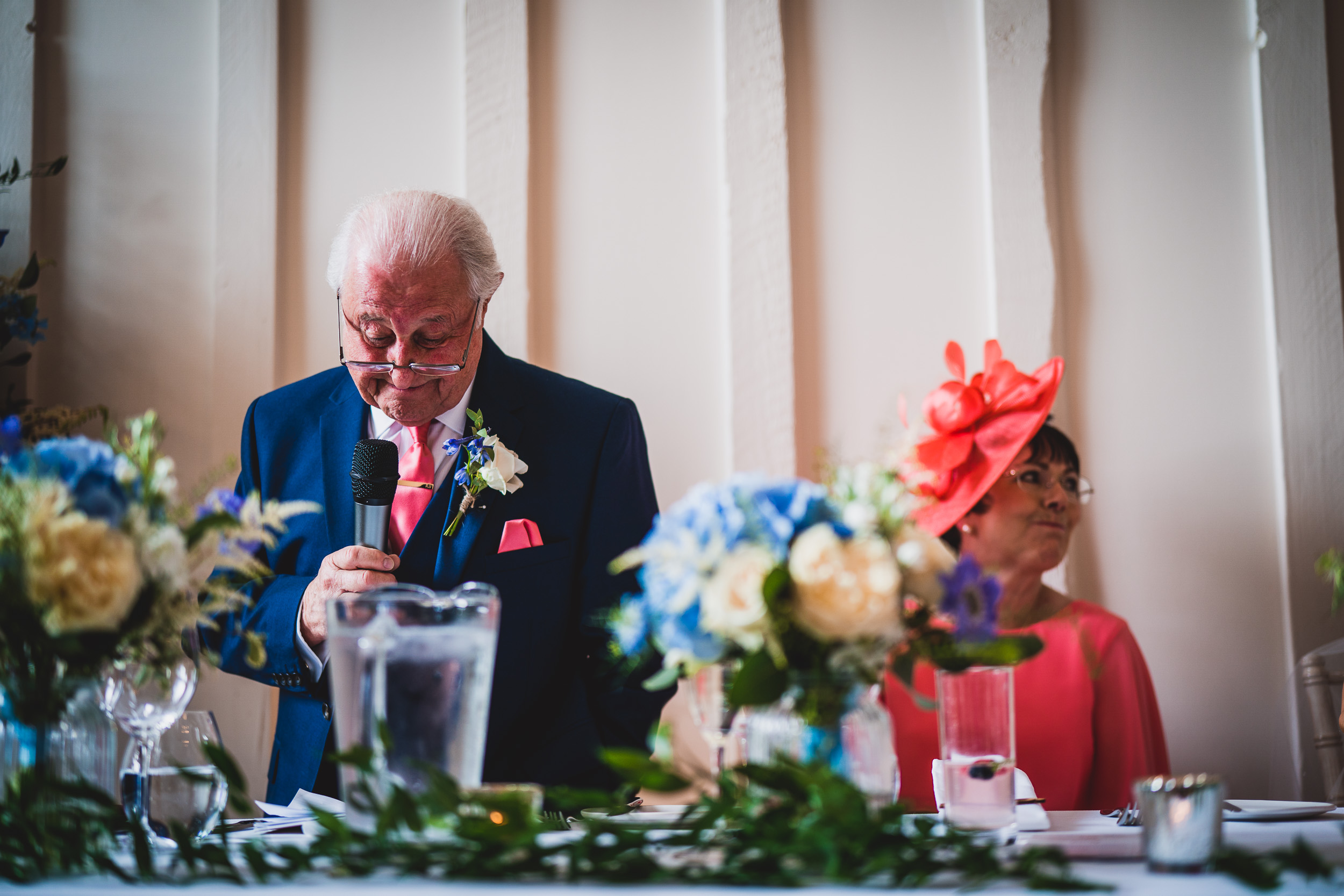 The groom, dressed in a suit, is delivering a speech at the wedding.