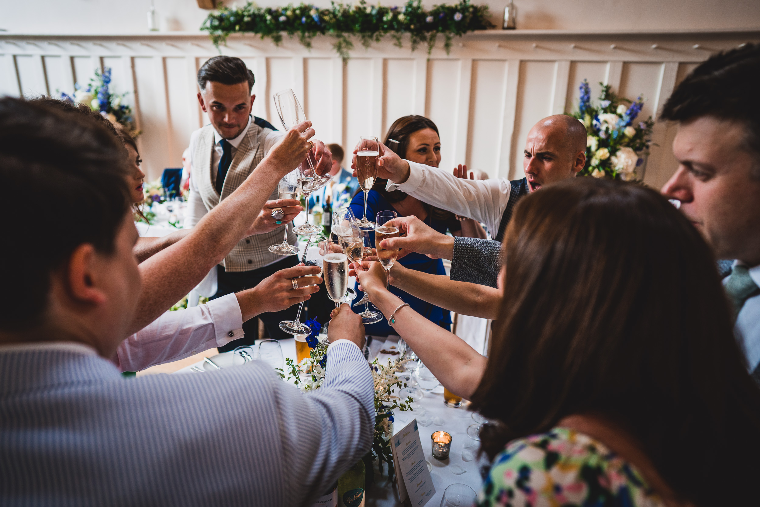 A bride and wedding photographer capture a group toasting at a wedding reception.