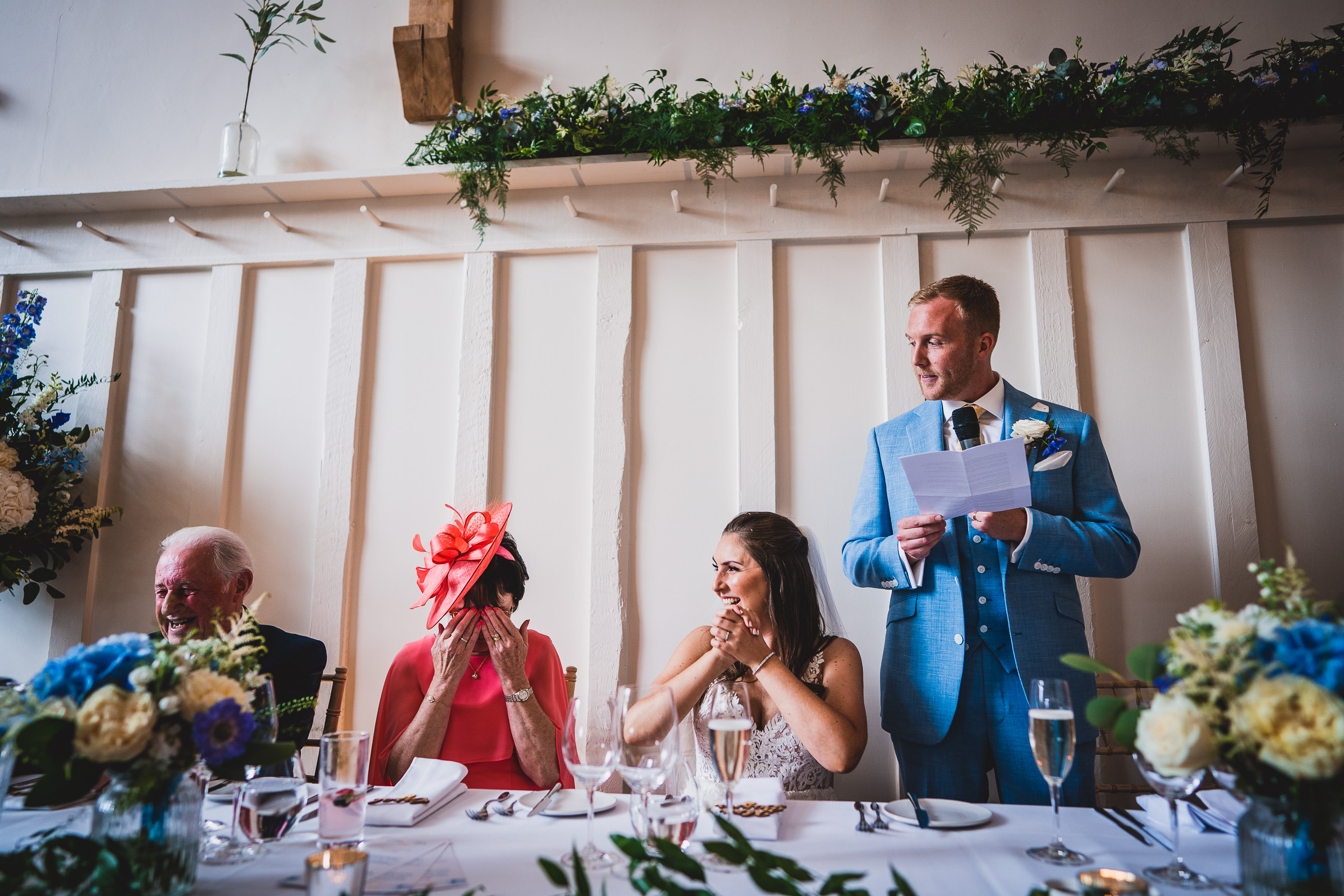 A man in a blue suit is giving a speech at a wedding.