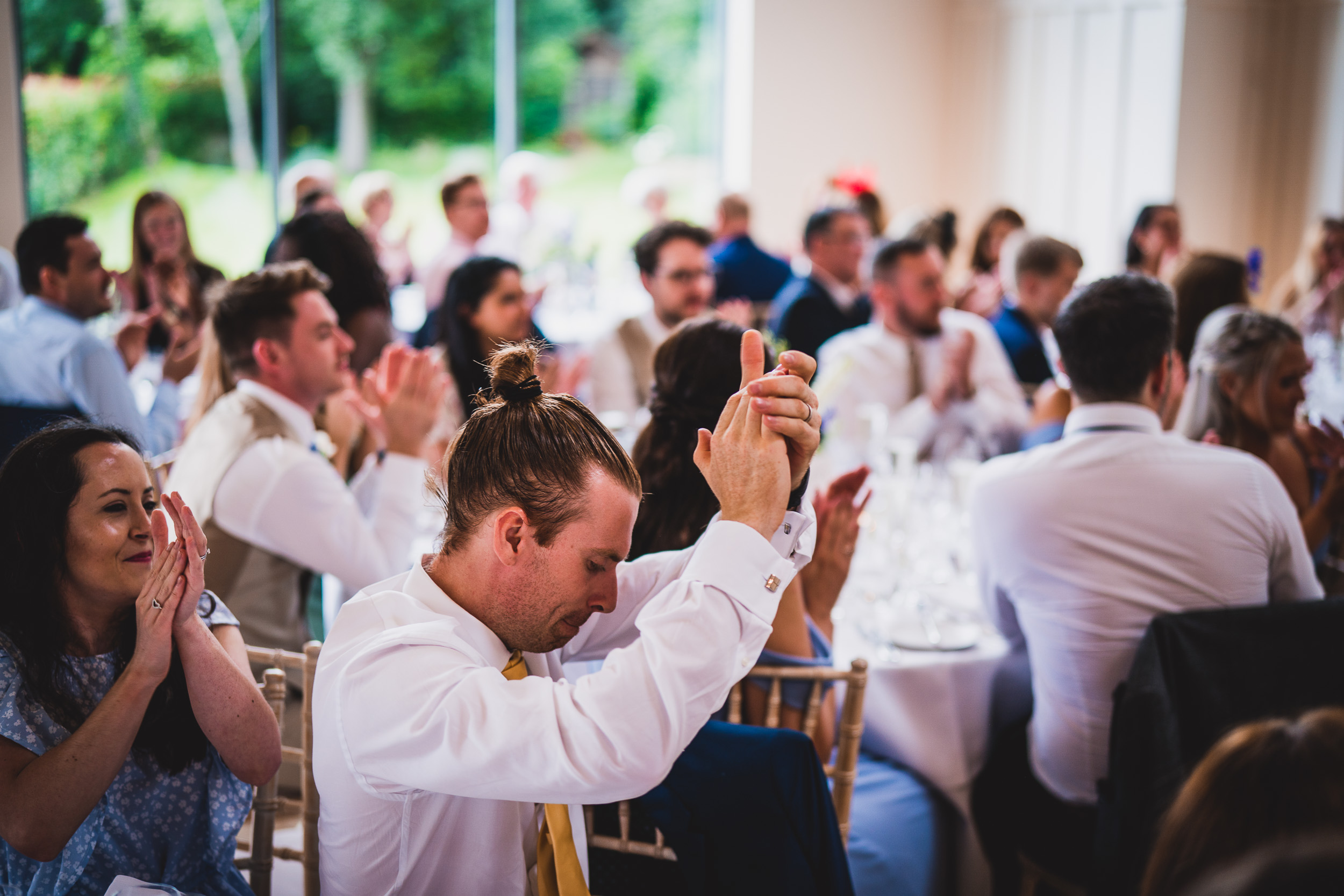 A bride's wedding photo capturing the joyful applause of a man at the reception.