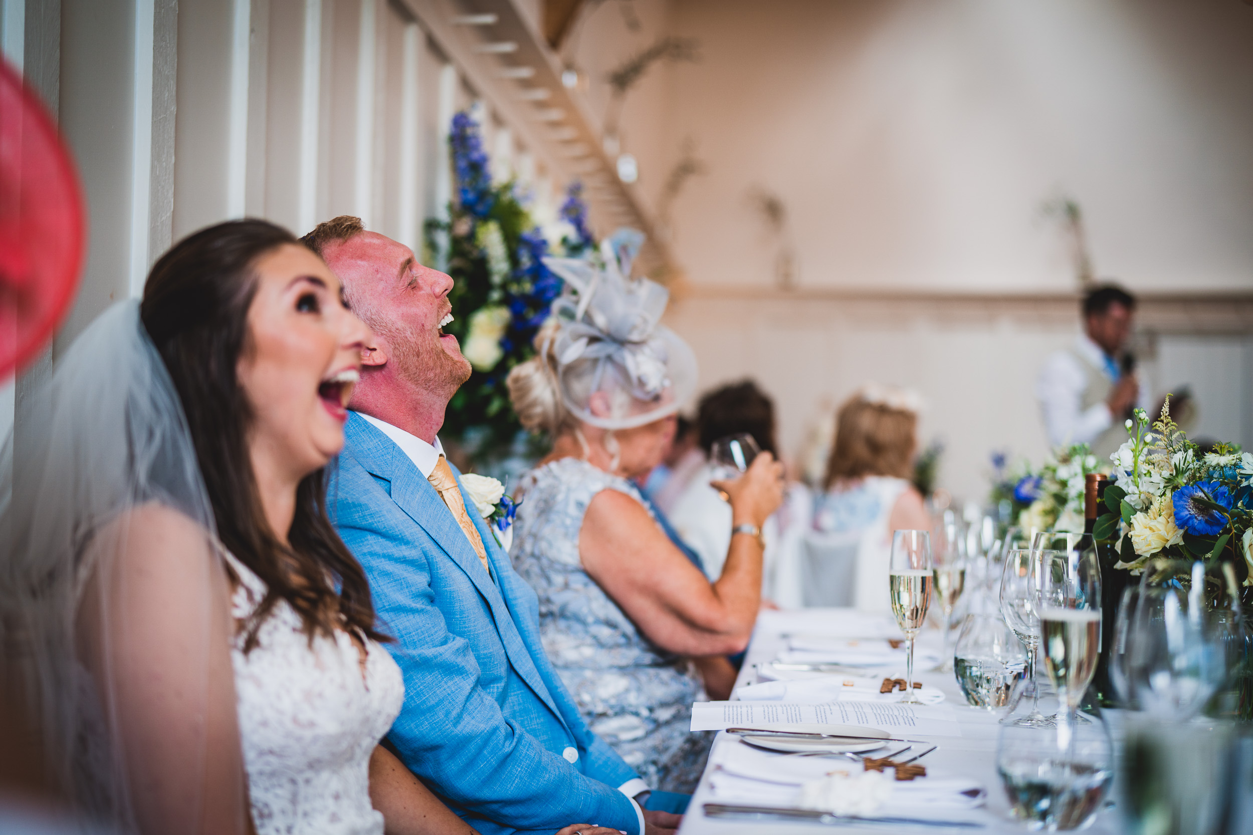 Bride and groom captured in joyful laughter by a wedding photographer.