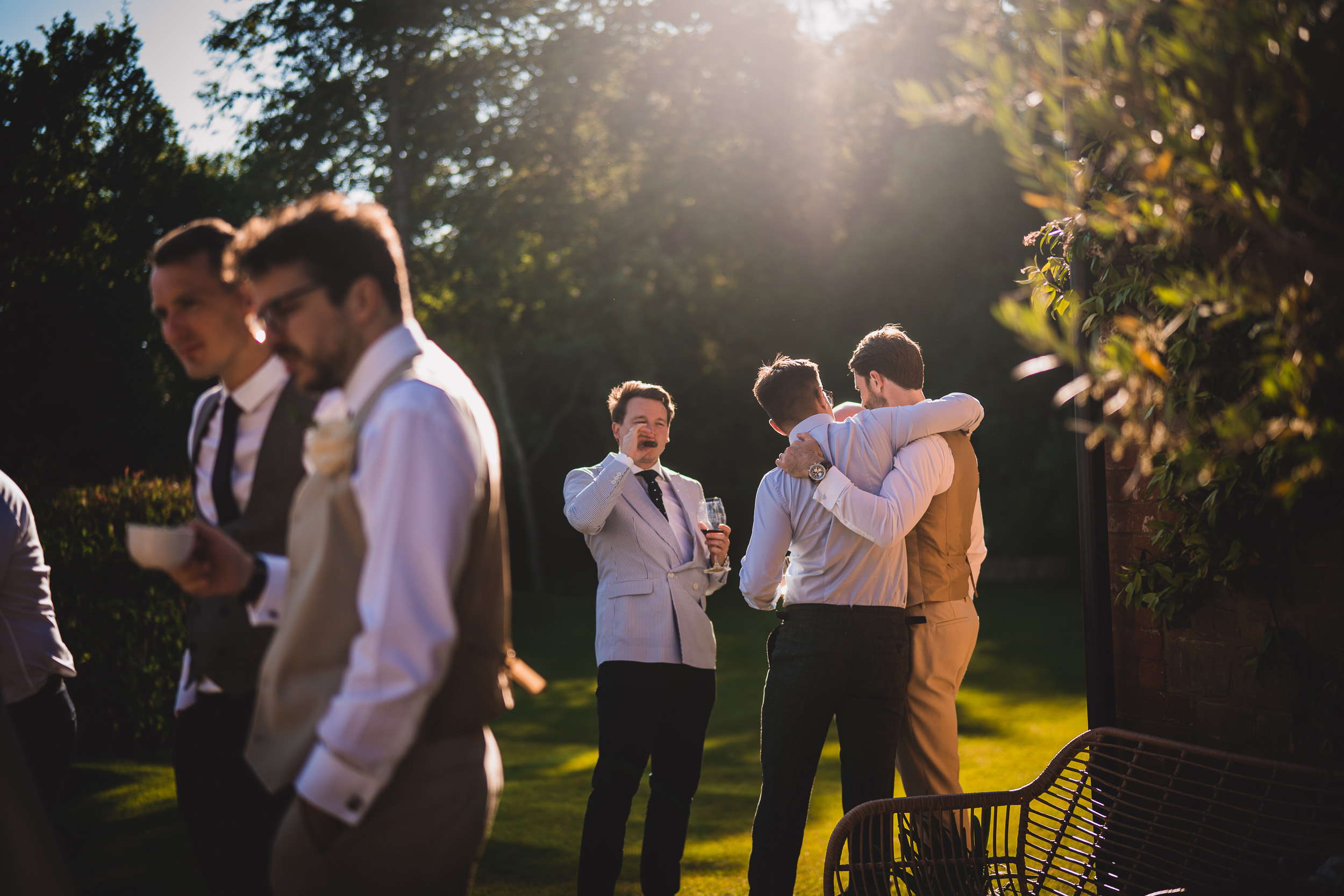 A group of groomsmen posing for a wedding photo in the sun.