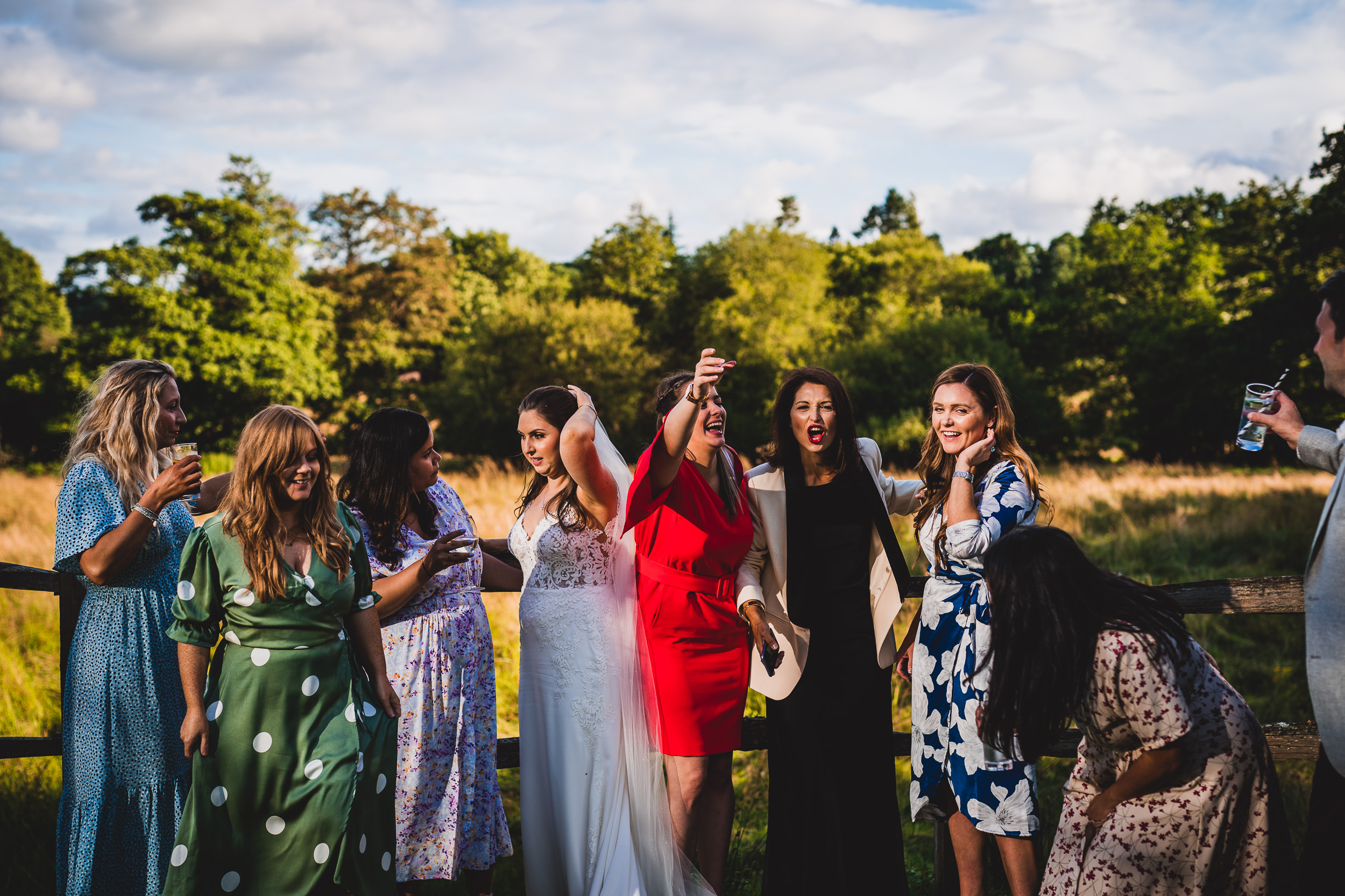 A group of bridesmaids posing for a wedding photographer in a field.