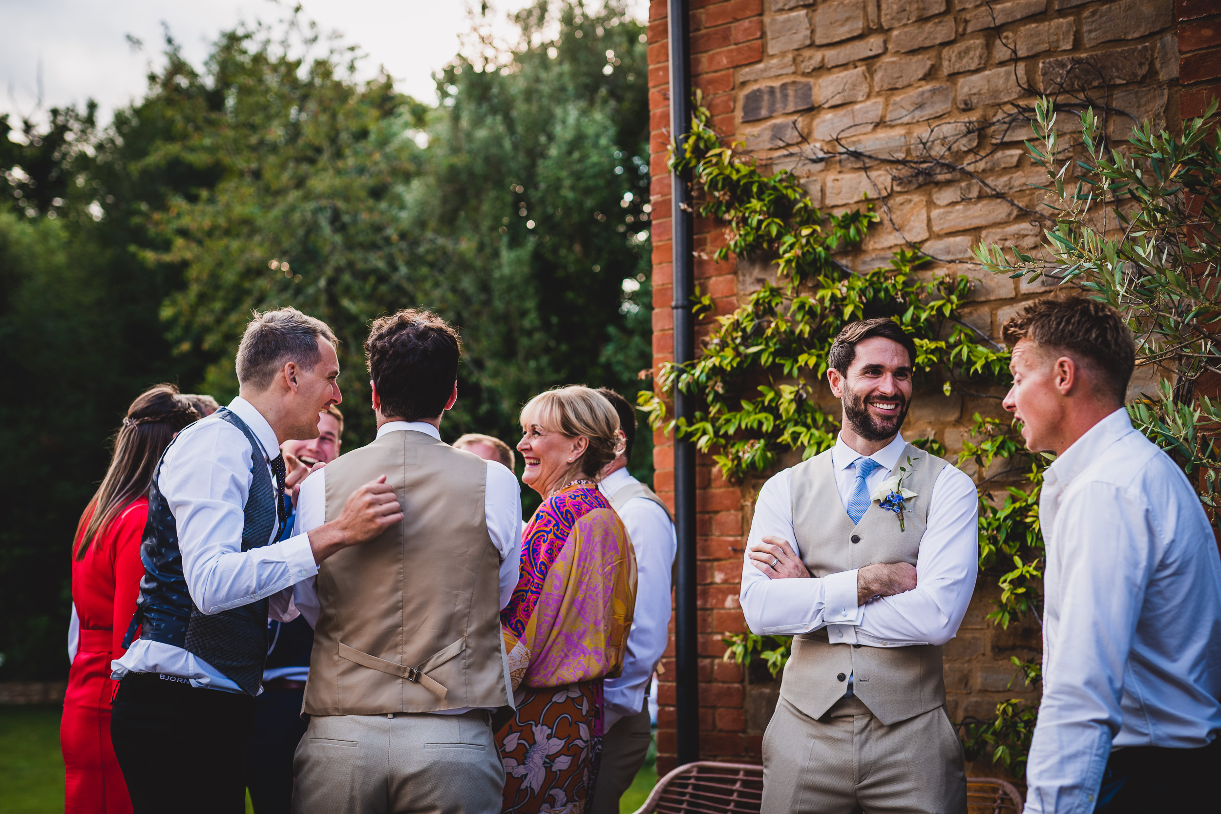 A group of groomsmen posing in front of a brick wall for a wedding photo.