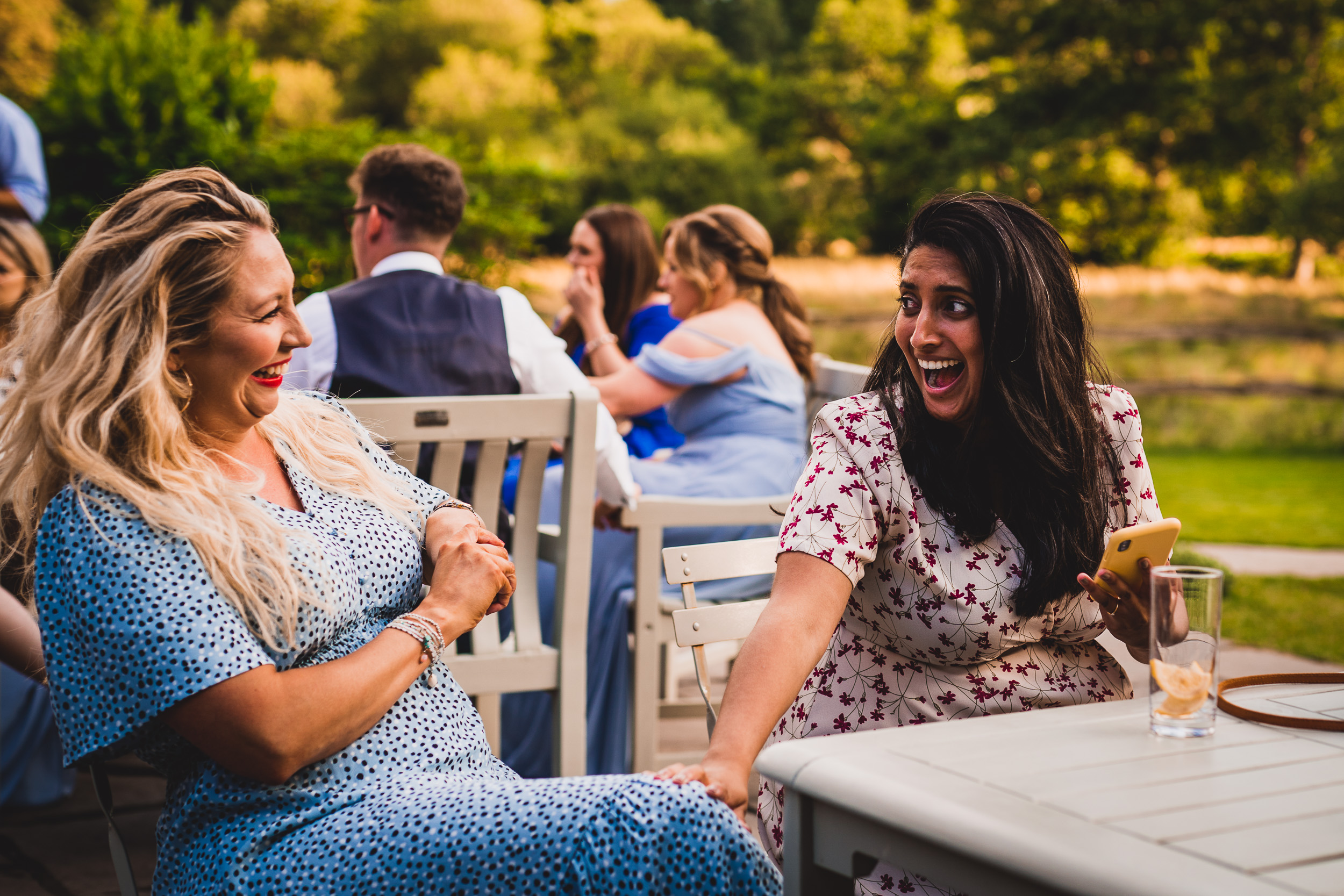 Wedding photographer captures bride and women laughing at outdoor wedding.