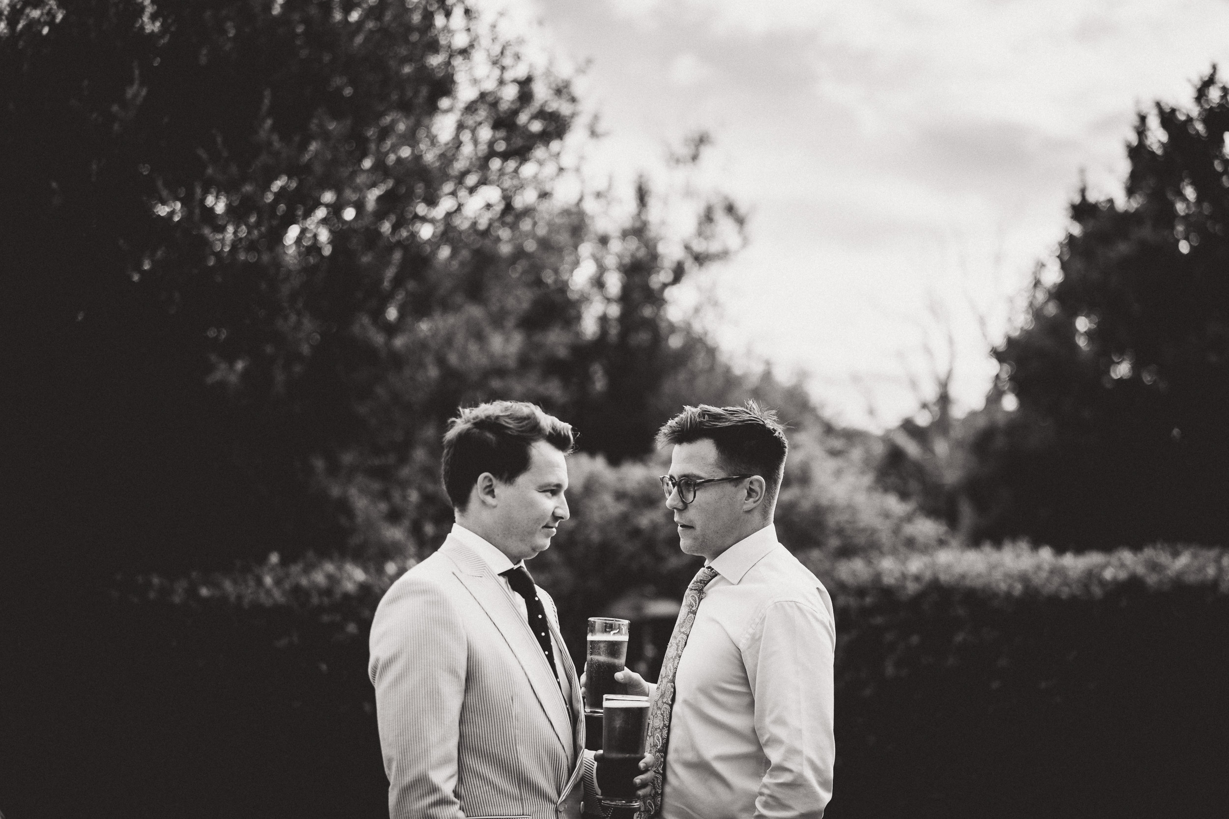 A black and white photo of two men standing next to each other at a wedding.