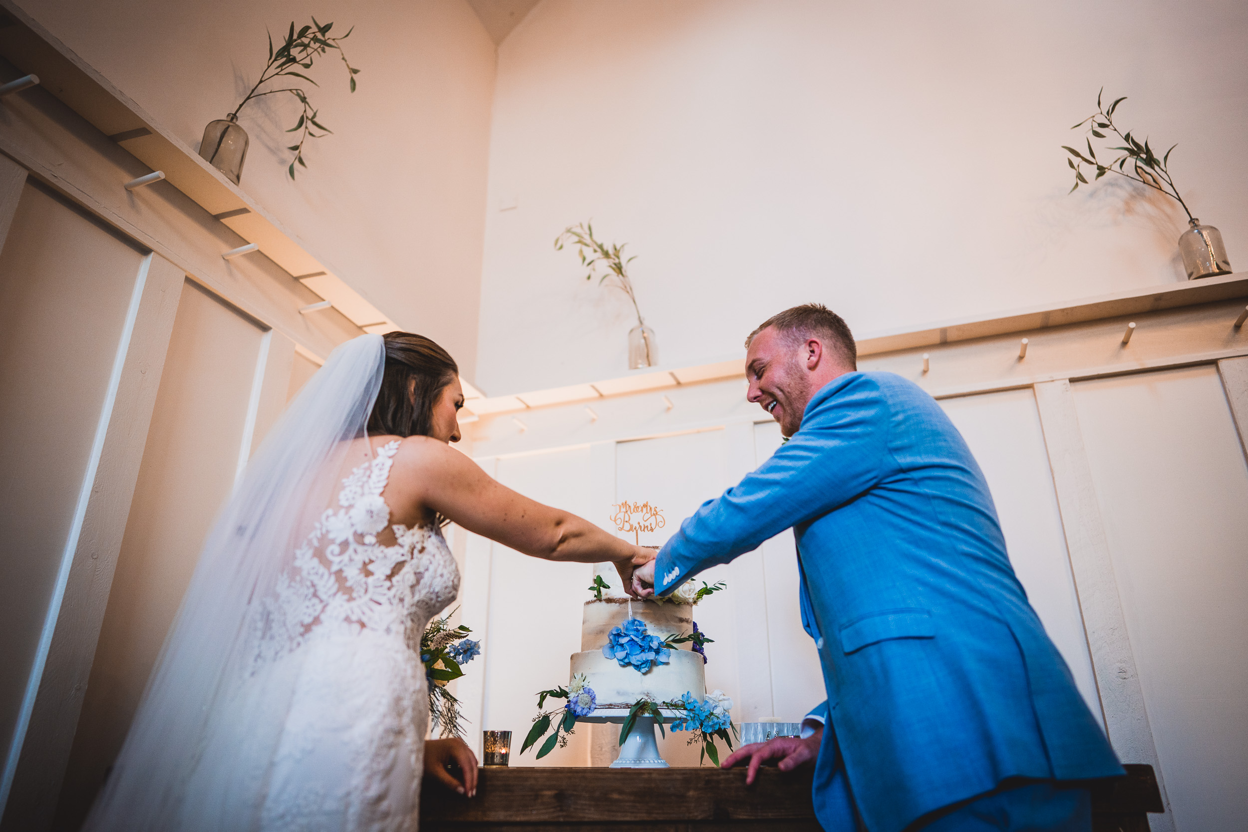 A wedding photographer capturing a bride and groom cutting their wedding cake.