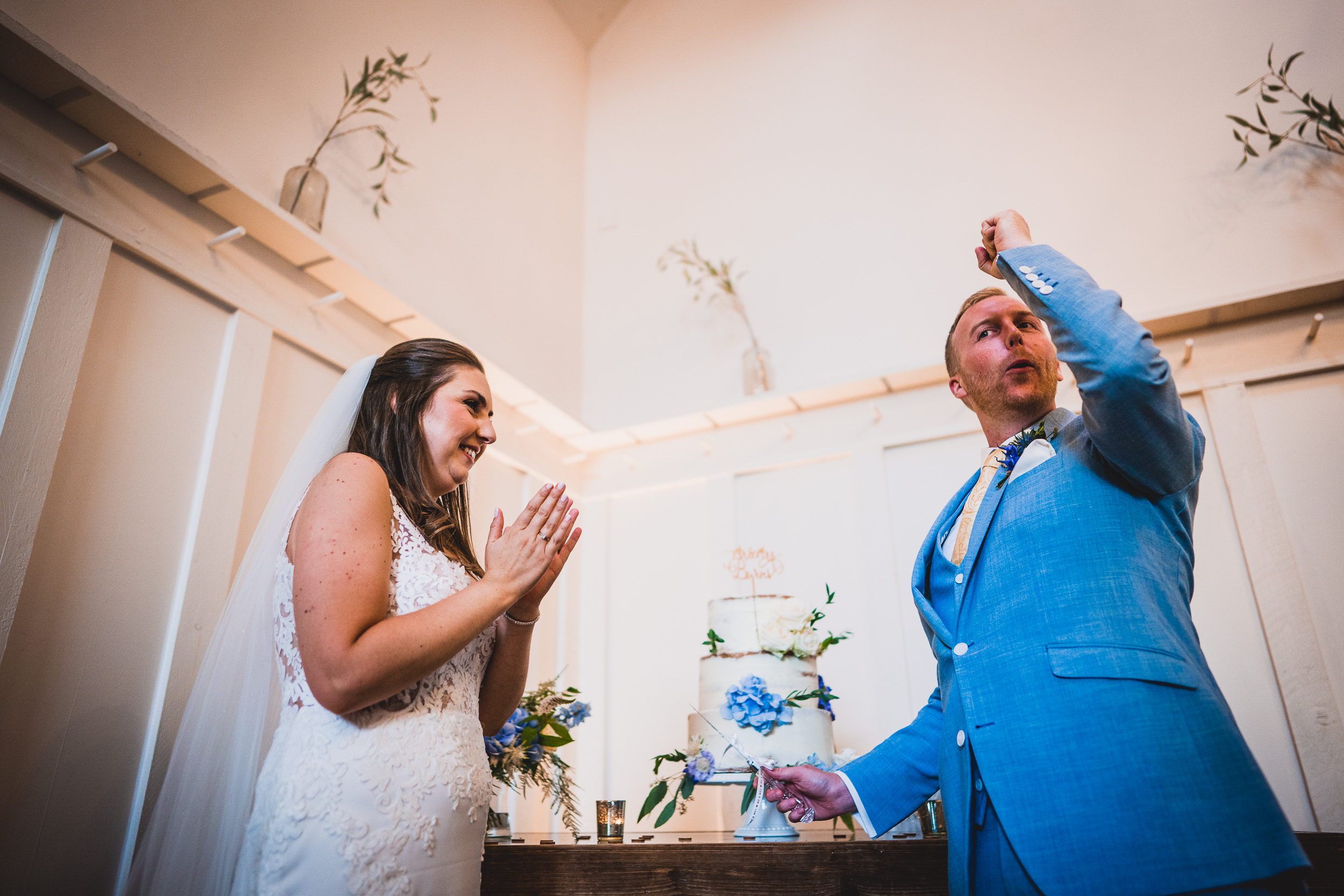 A wedding photo capturing the groom and bride cutting their cake.