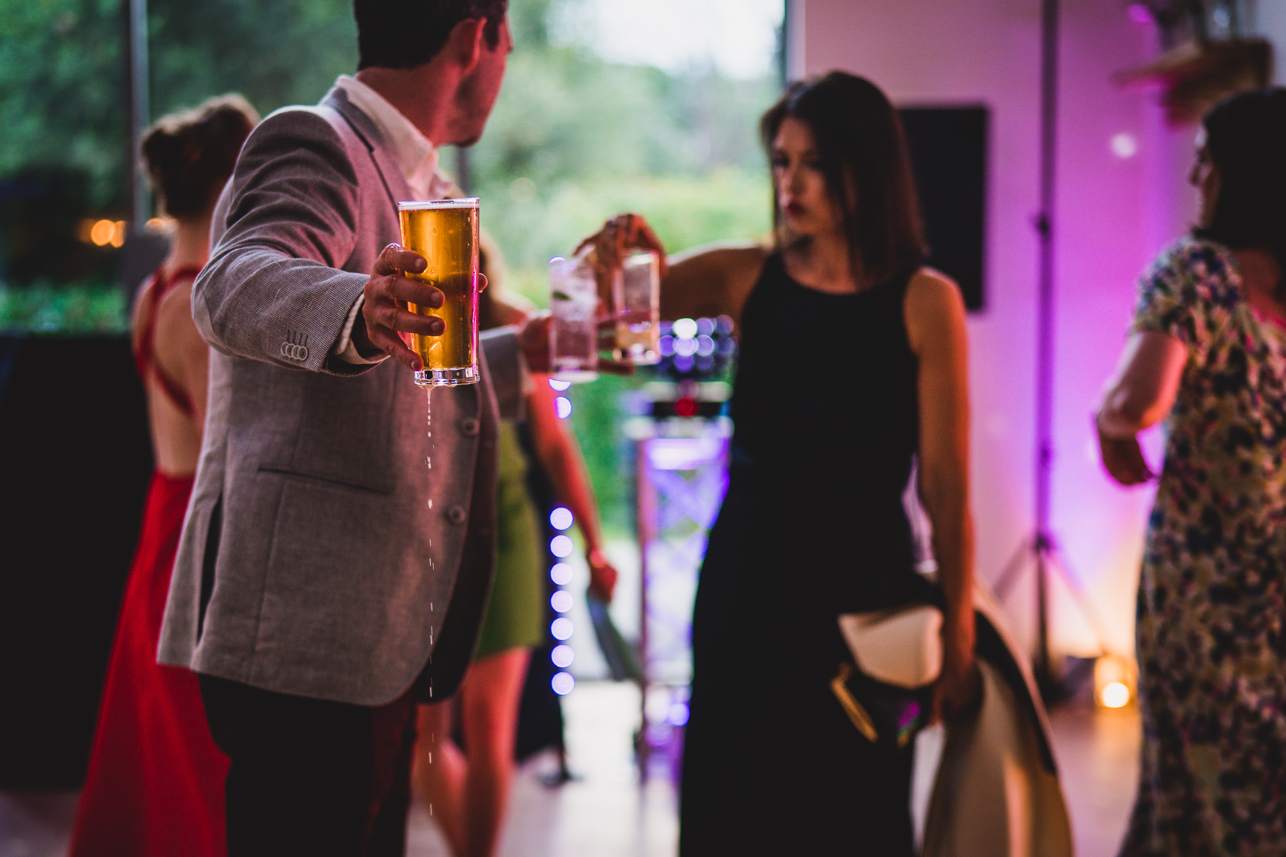 A groom and a wedding photographer capturing a party moment with beer.