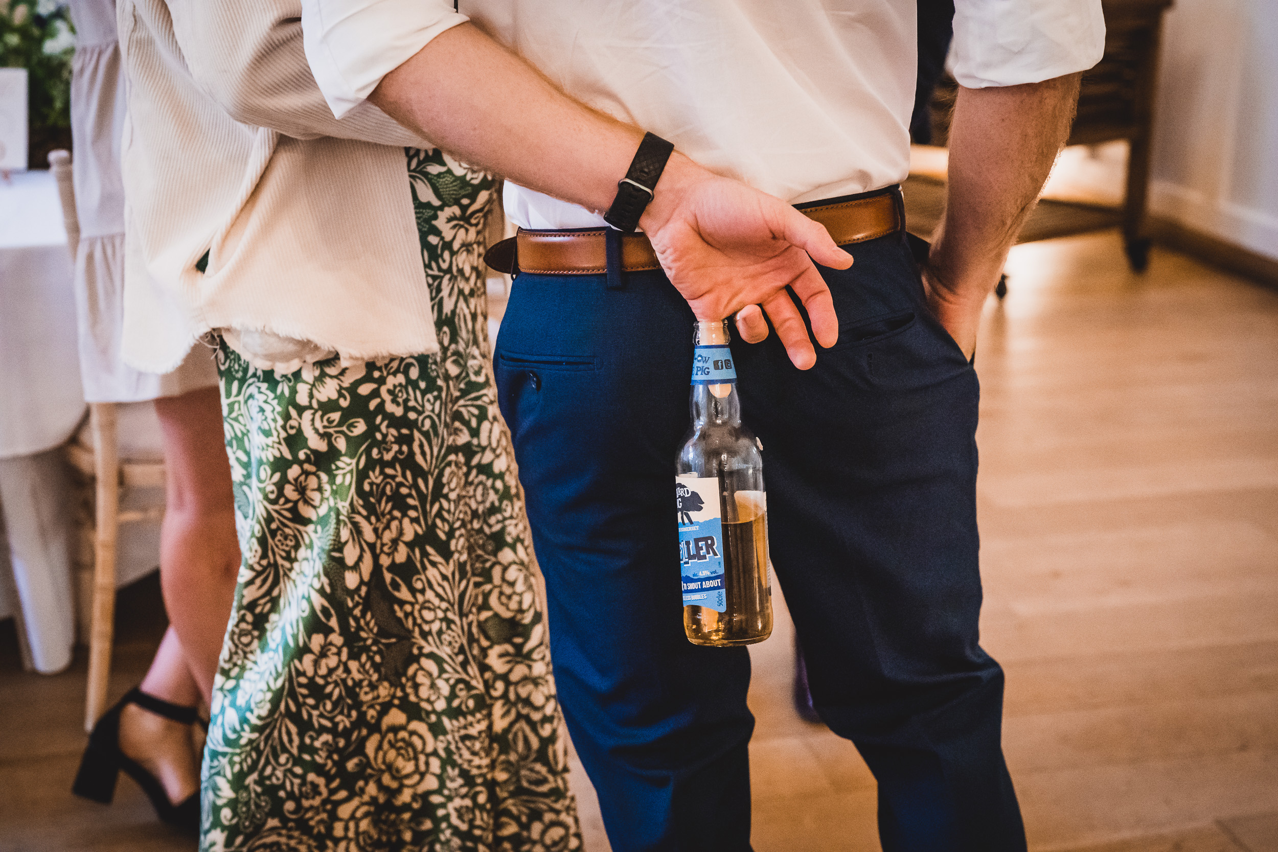 A groom is holding a bottle of beer in his hand.