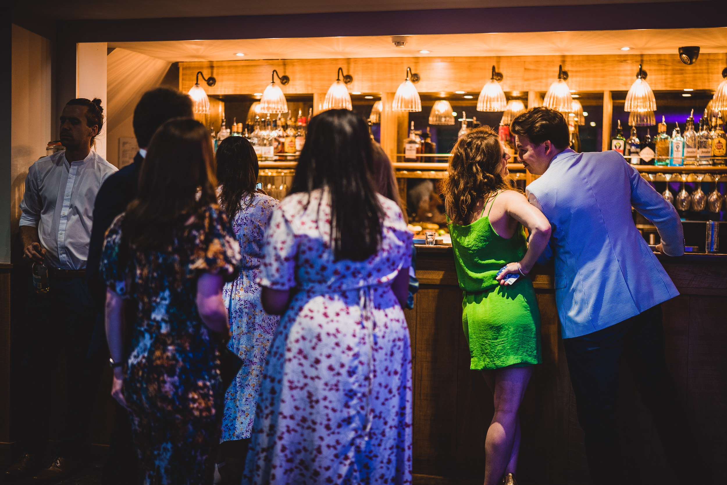 A wedding photographer captures moments of a bride and groom at a bar.