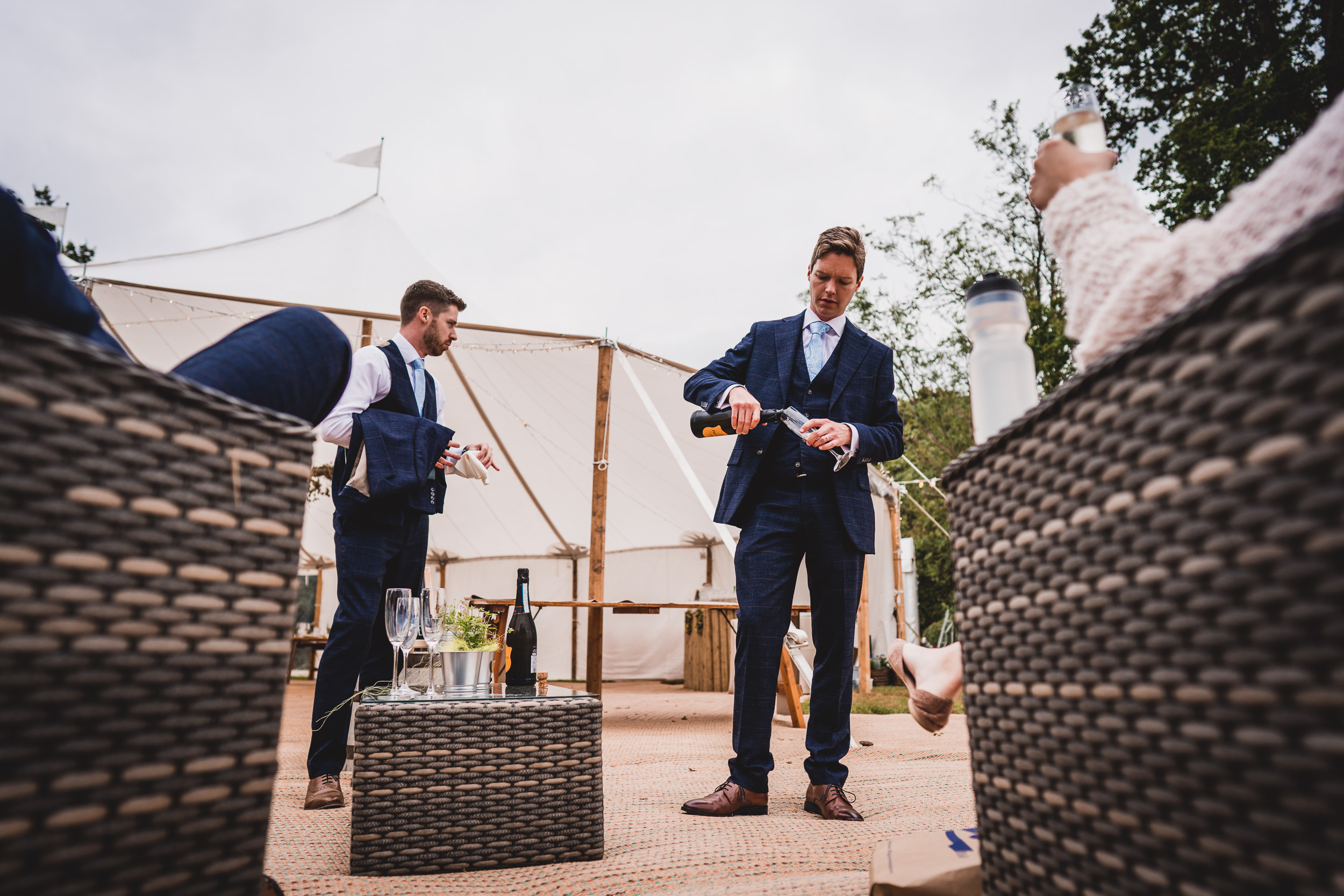 A group of groomsmen in suits standing in front of a wedding tent.