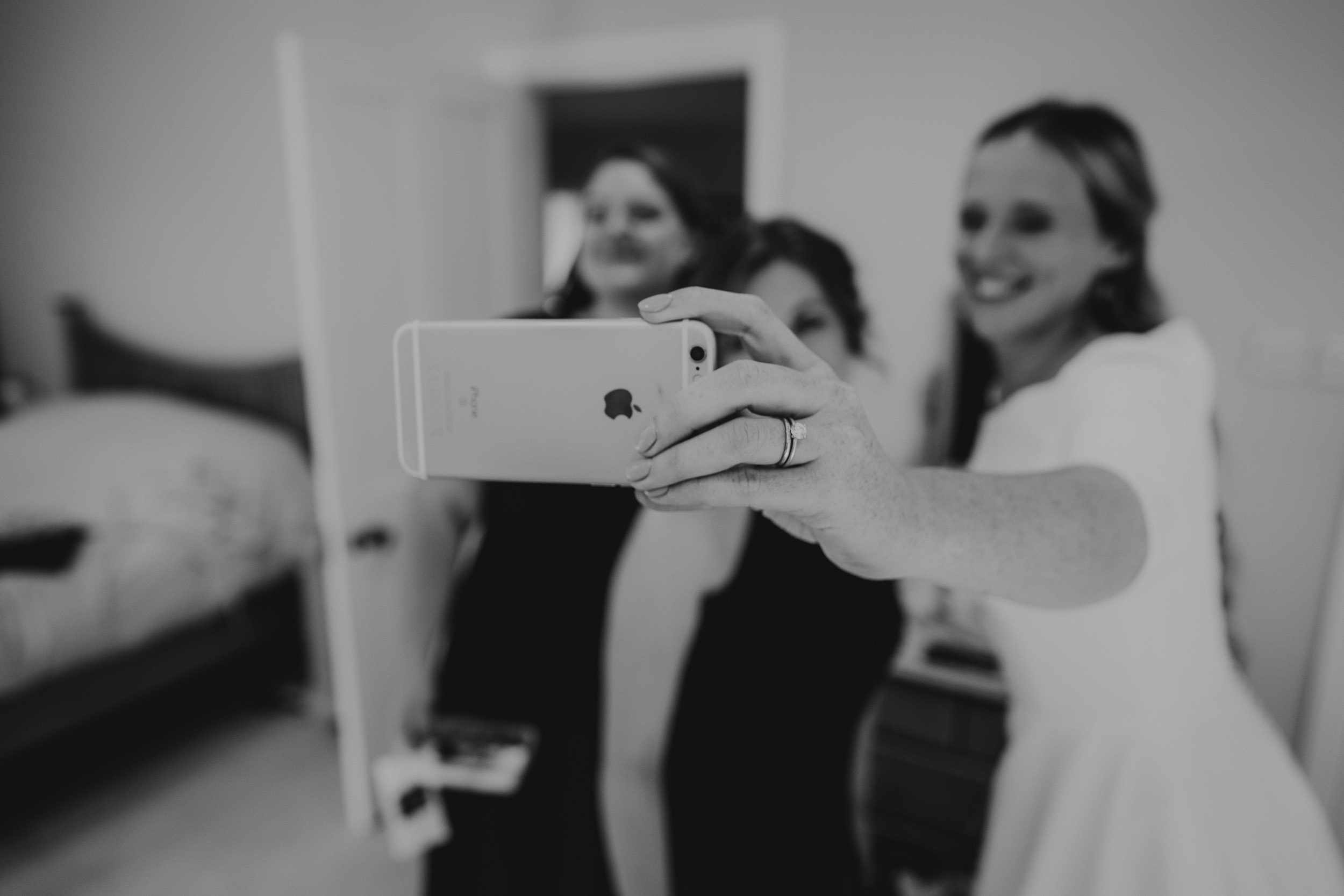 Bridesmaids capturing a mirror selfie at a wedding.