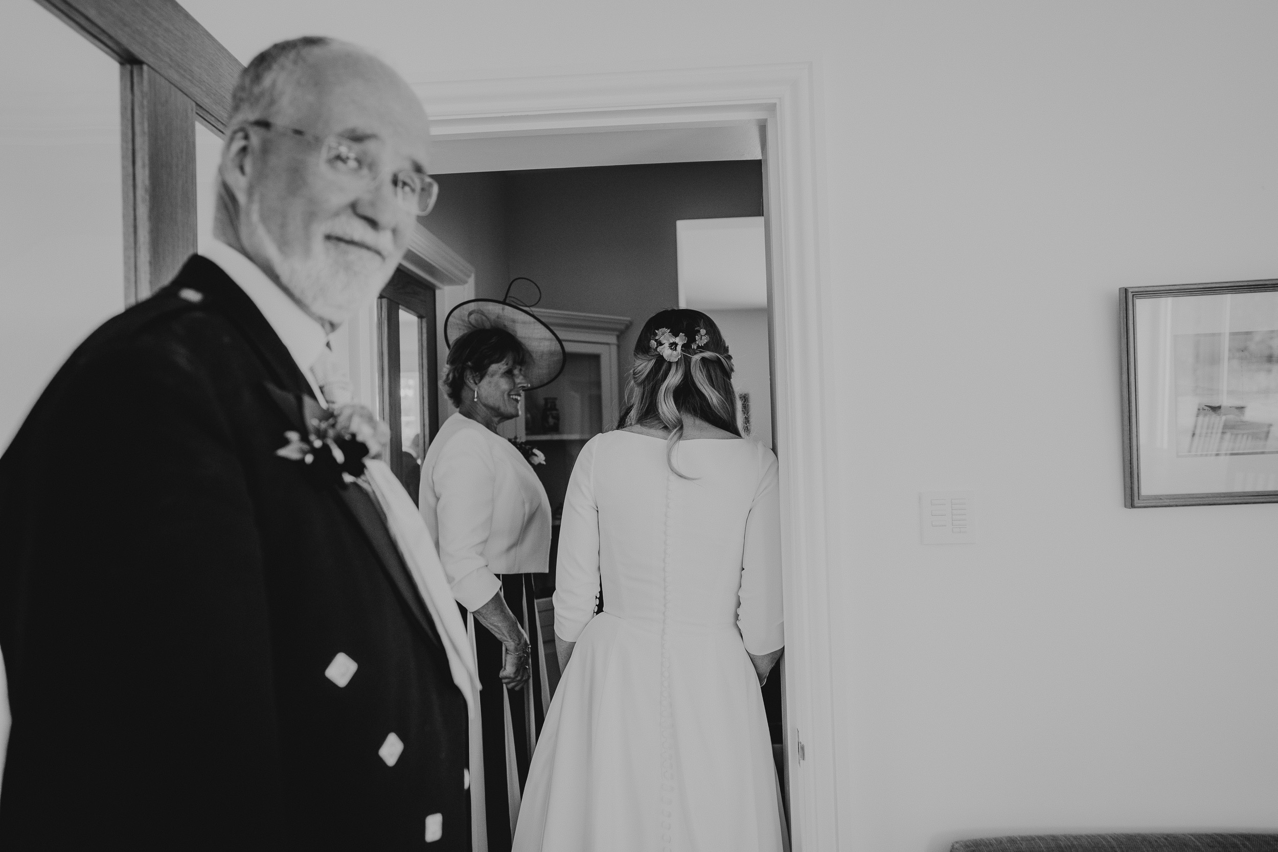 A groom in a kilt is standing next to a bride for their wedding photo.