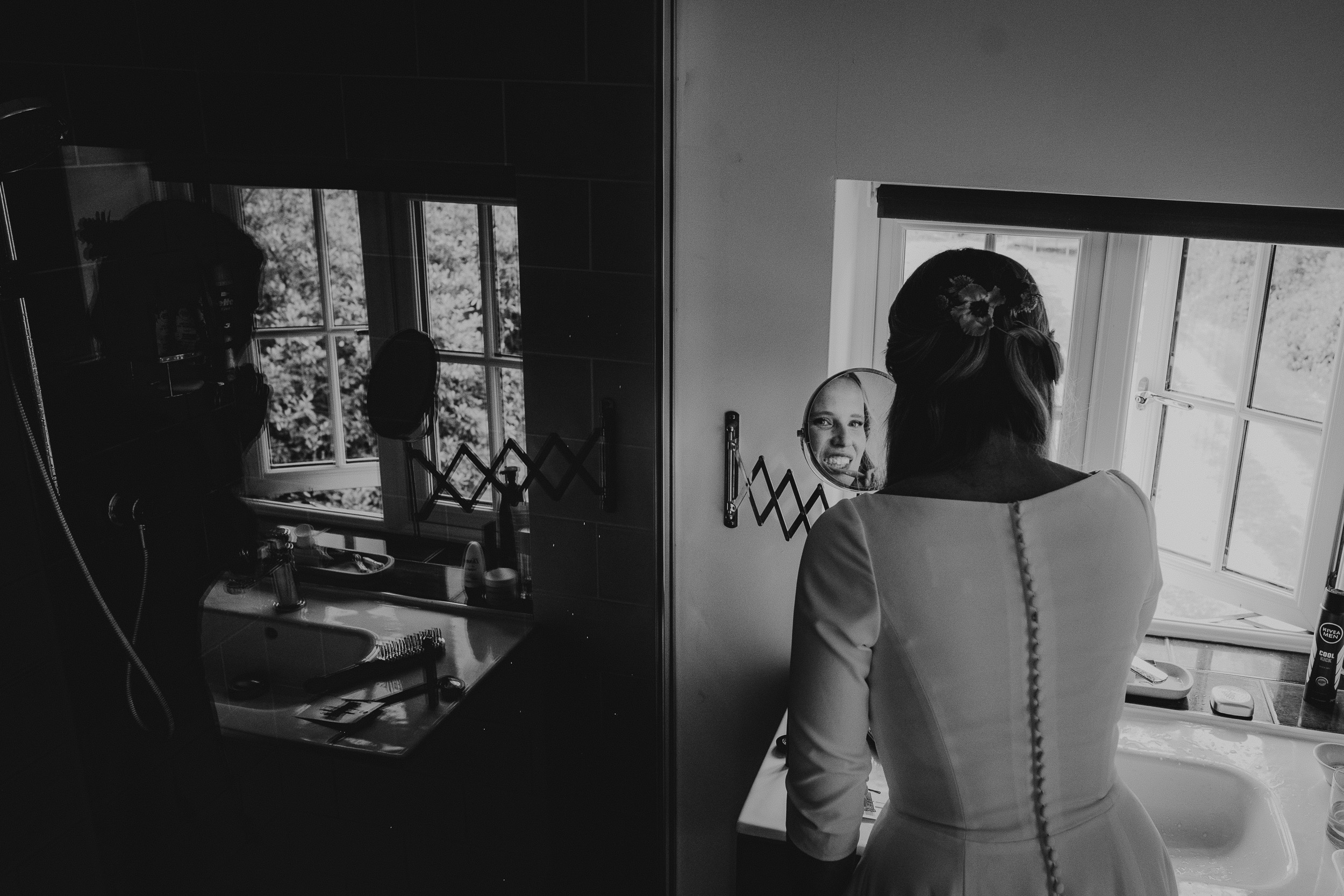 A wedding bride admires herself while standing before a mirror.