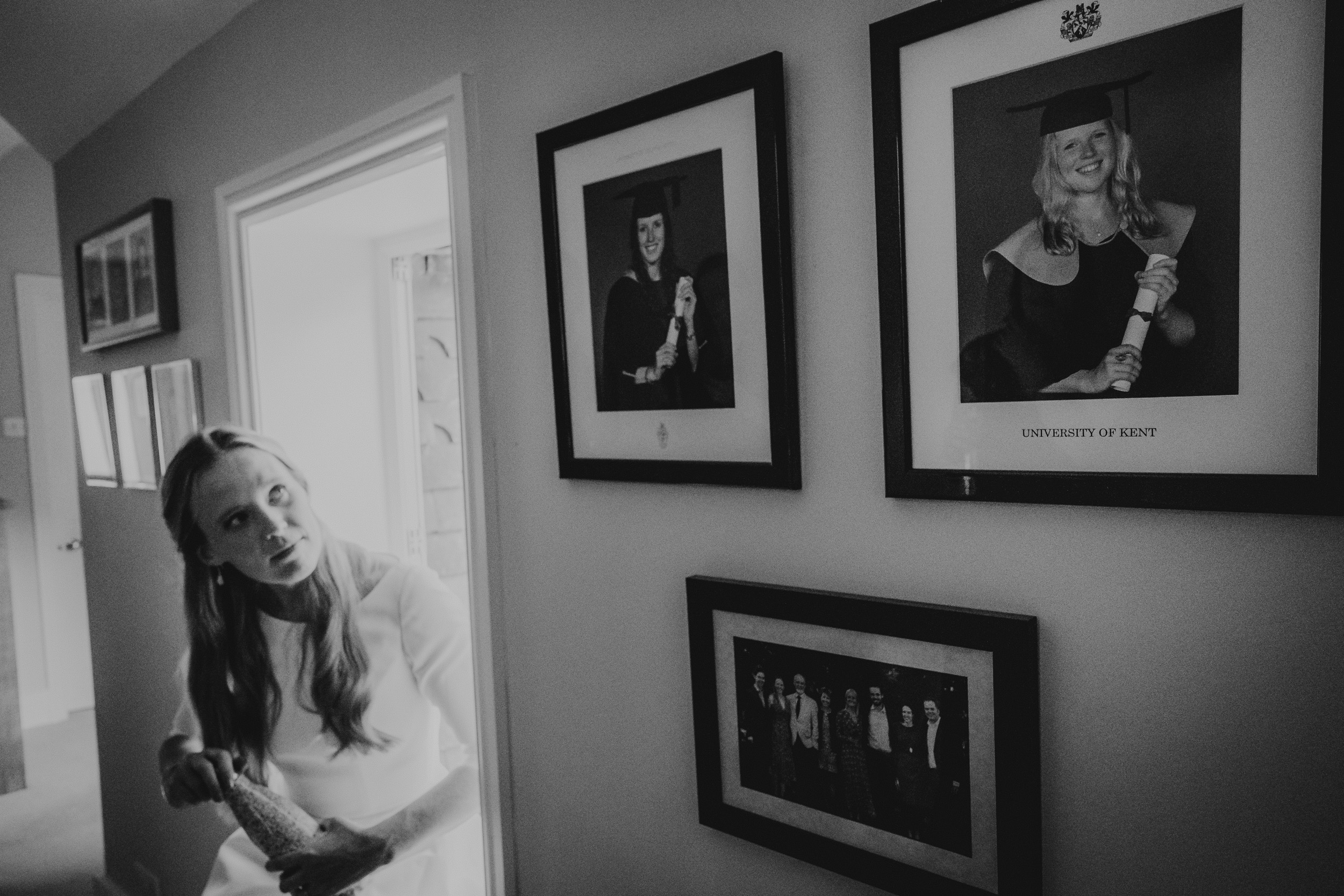 A woman fondly admiring framed wedding photos of the bride and groom in a hallway.