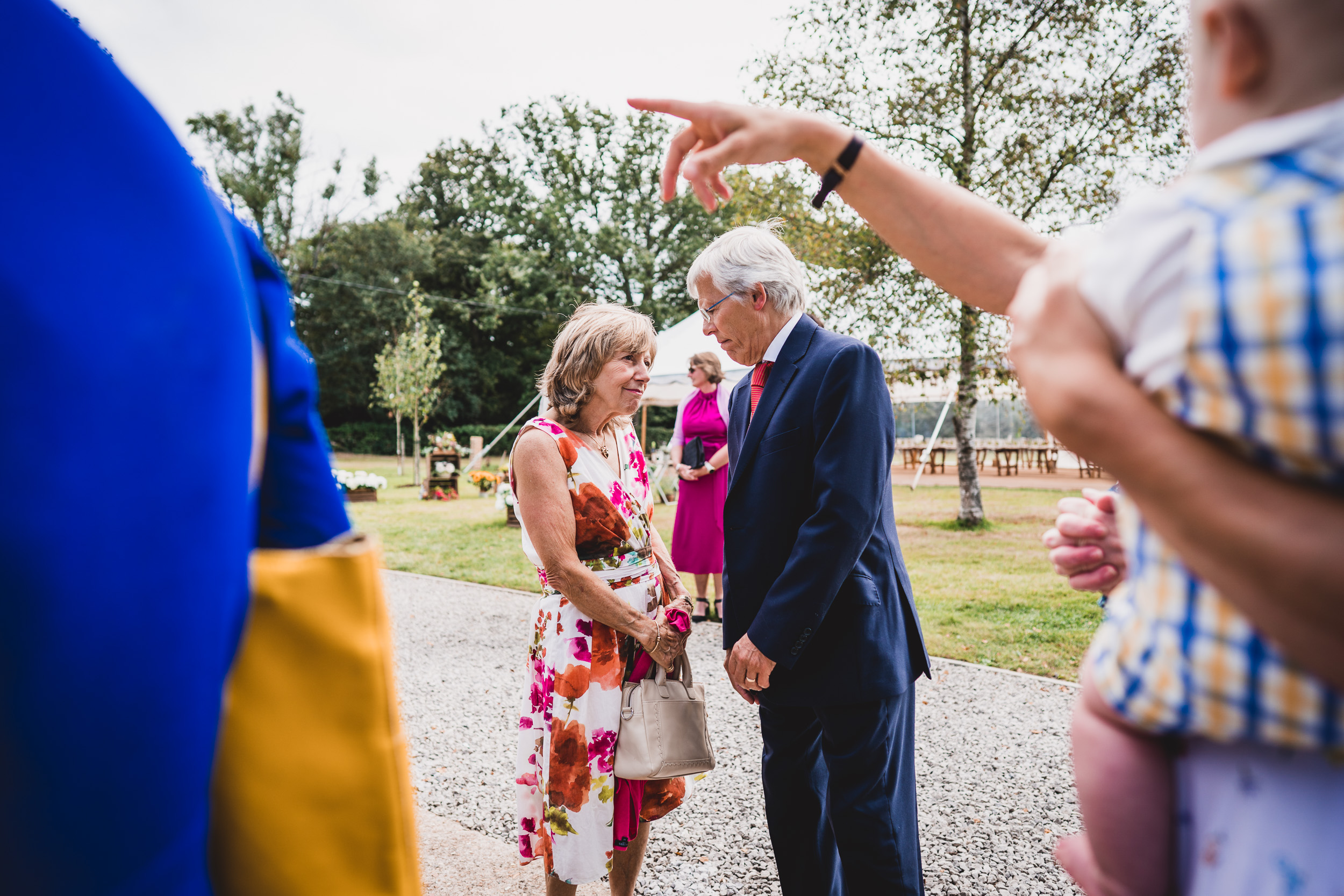 A groom interacts with a woman while posing for wedding photos.