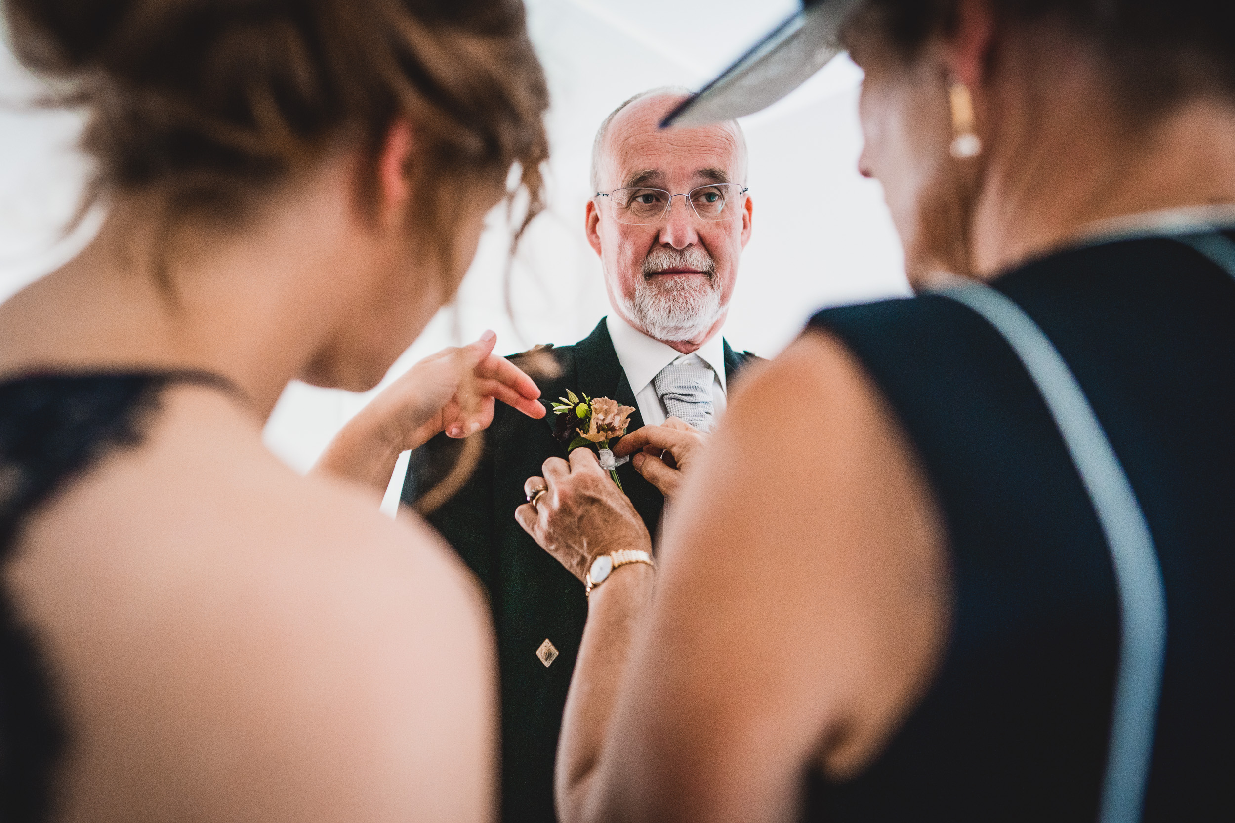 The groom carefully fastens the boutonniere on the bride, captured by the wedding photographer.