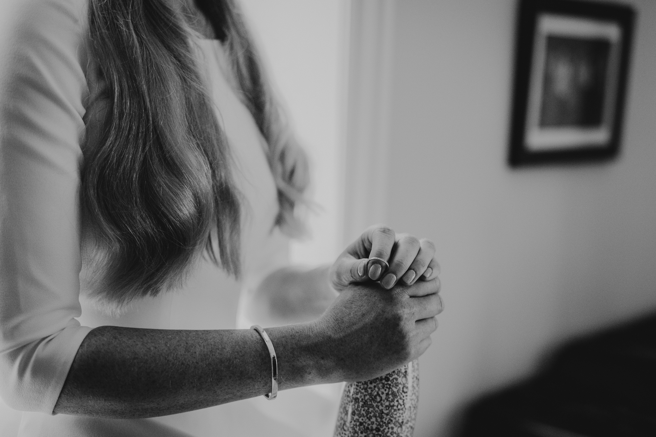 A black and white wedding photo of a bride holding her wedding ring.