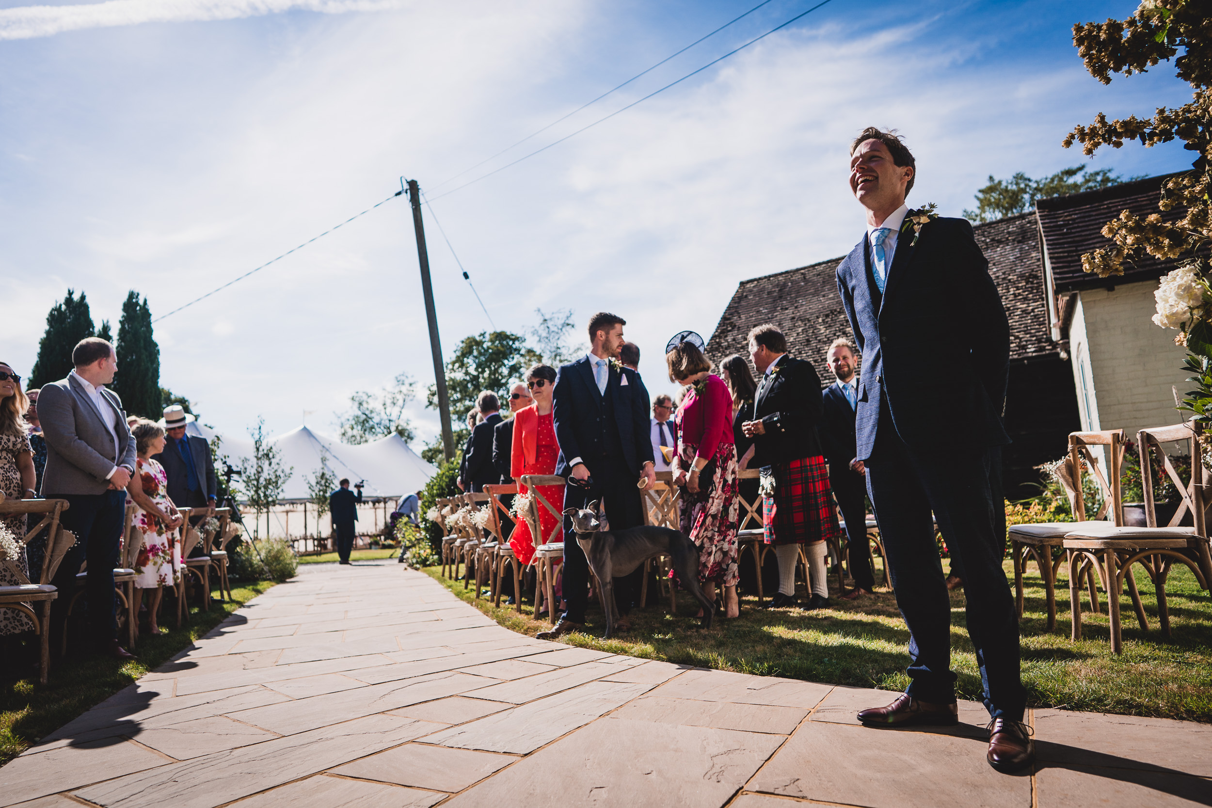 A groom and wedding photographer capture the precious moments as a bride walks down the aisle at a wedding ceremony.