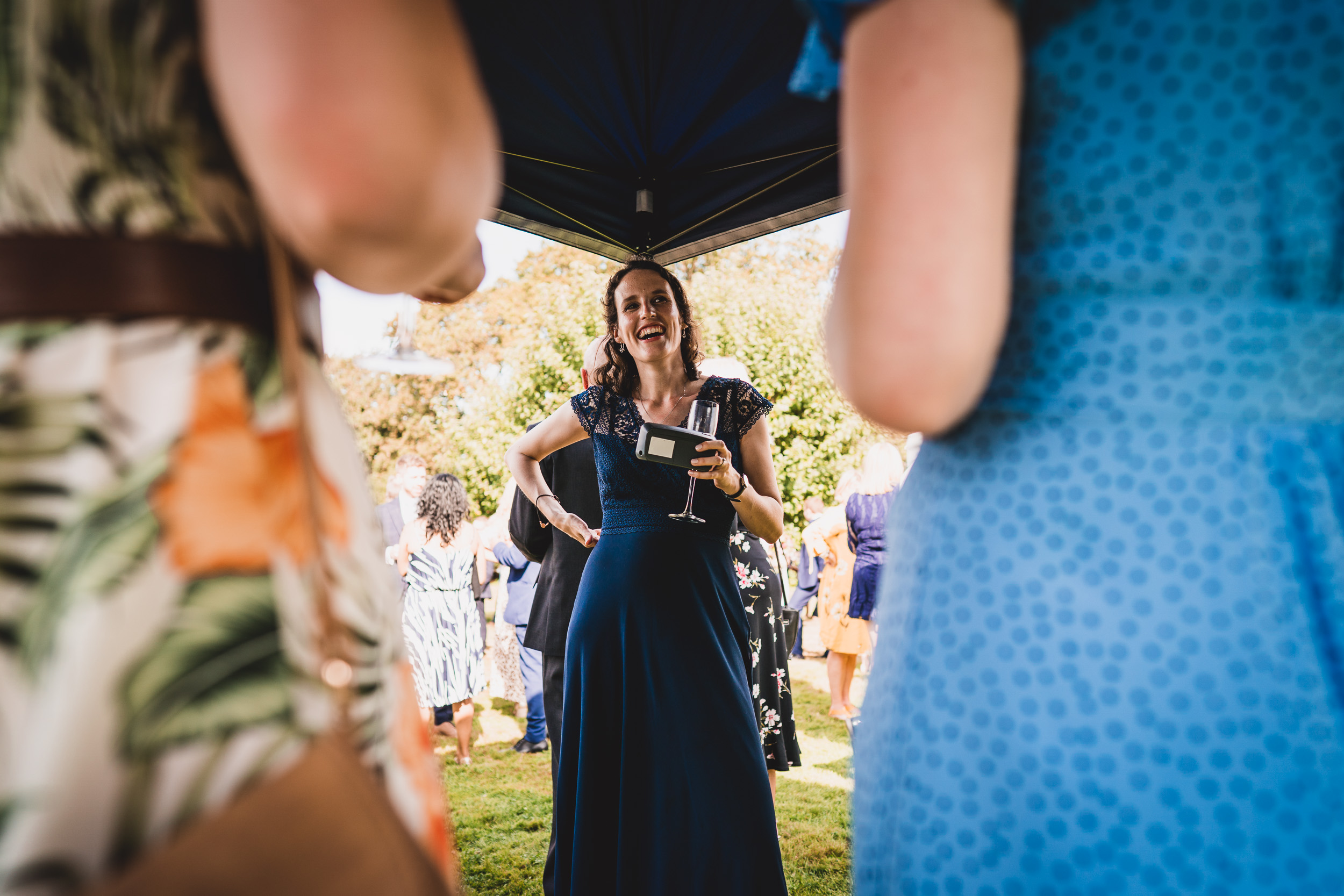 A woman in a blue dress is holding a glass of wine at a wedding.