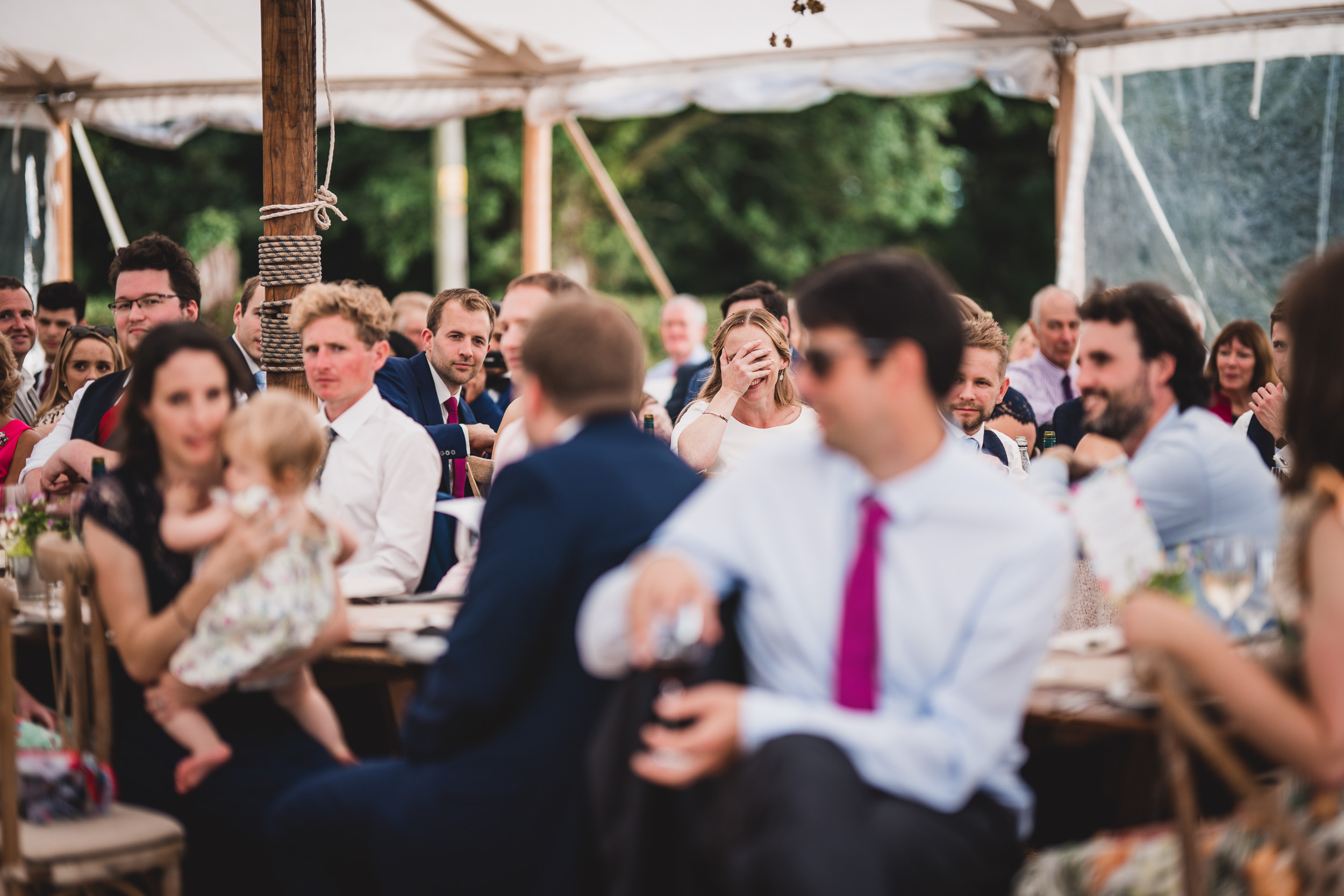 A group of people sitting in a tent at a wedding ceremony.