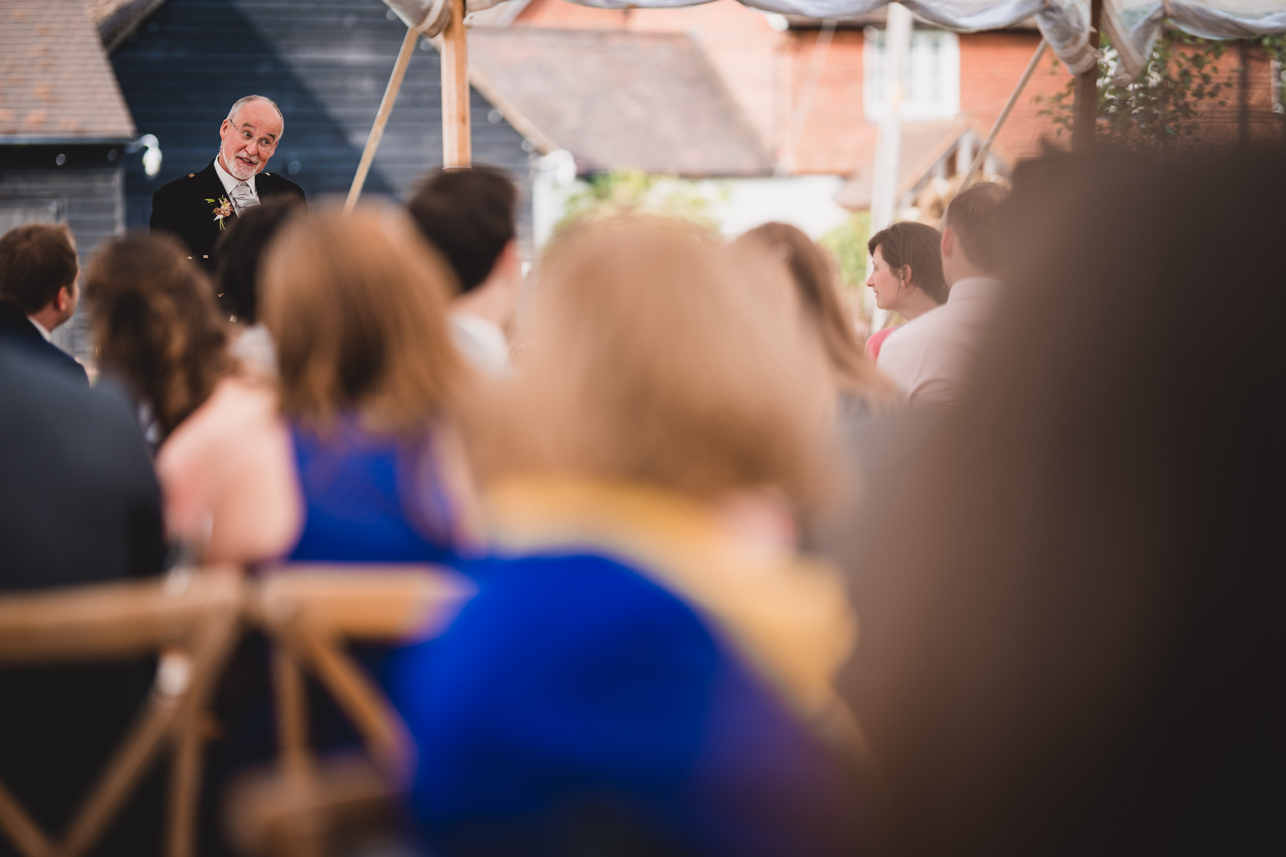 A groom delivering a speech at an outdoor wedding, captured by the wedding photographer.