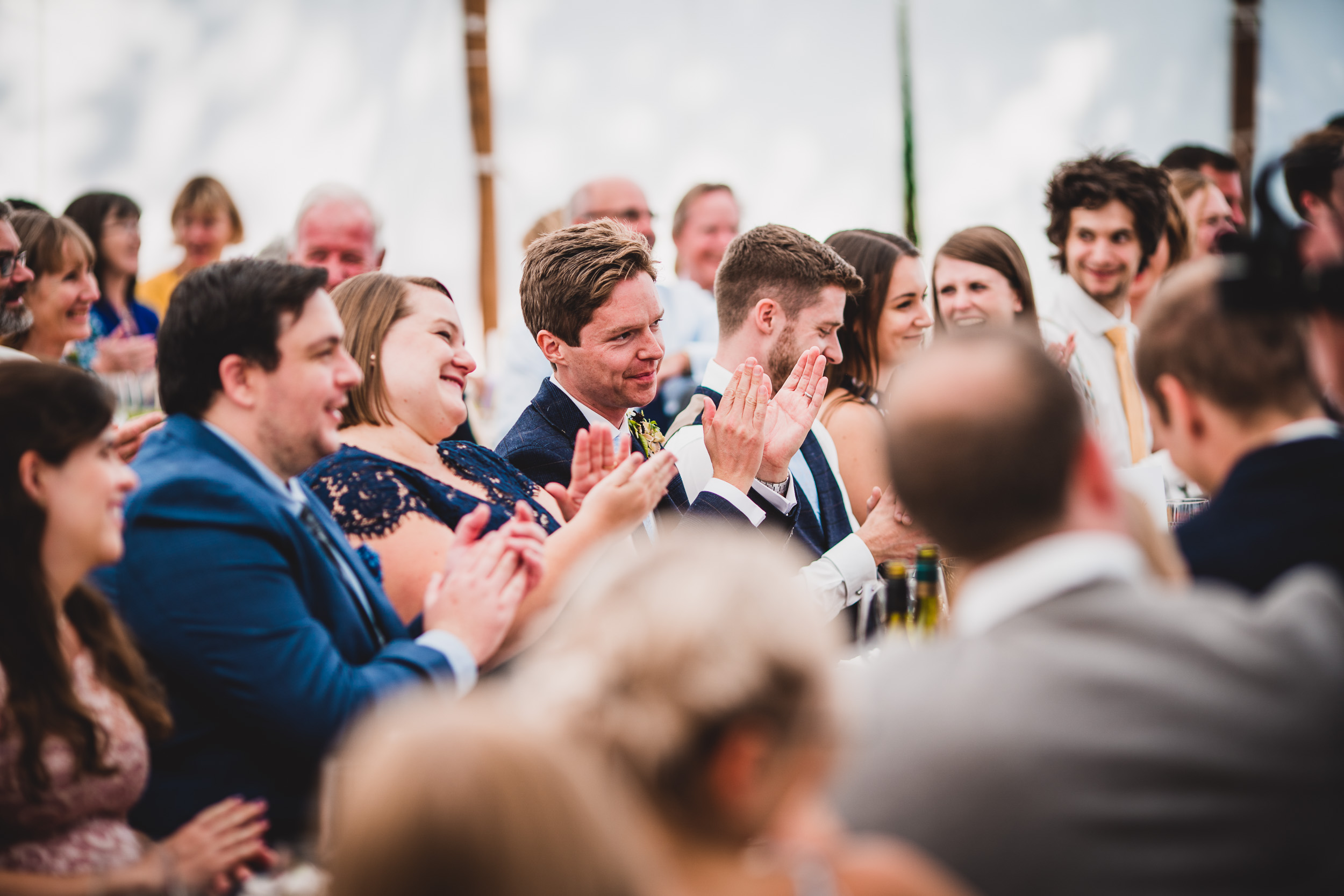 A group of people clapping at a wedding reception for the bride and groom.