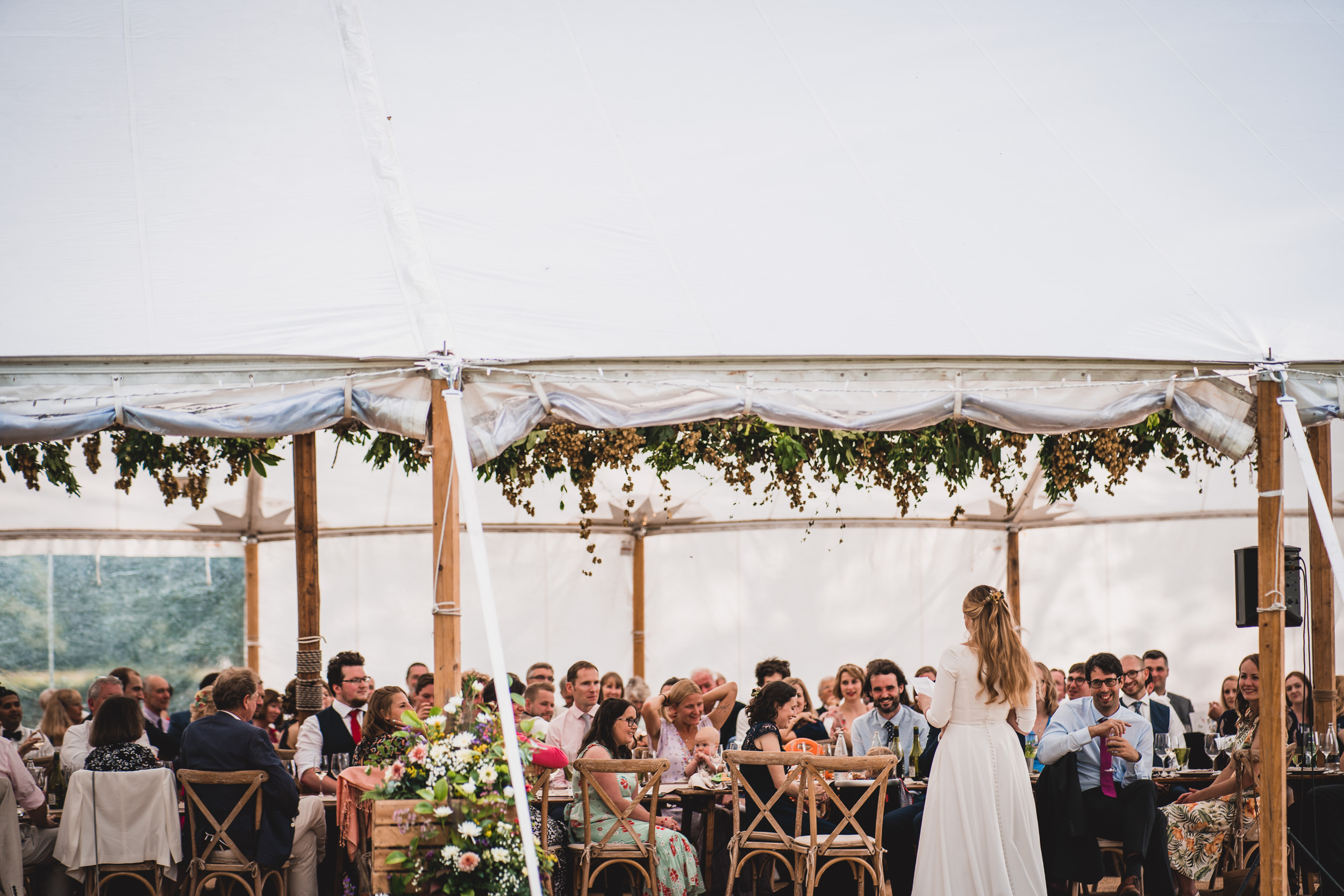 A bride at her wedding reception in a white tent, capturing memorable moments for her wedding photo.