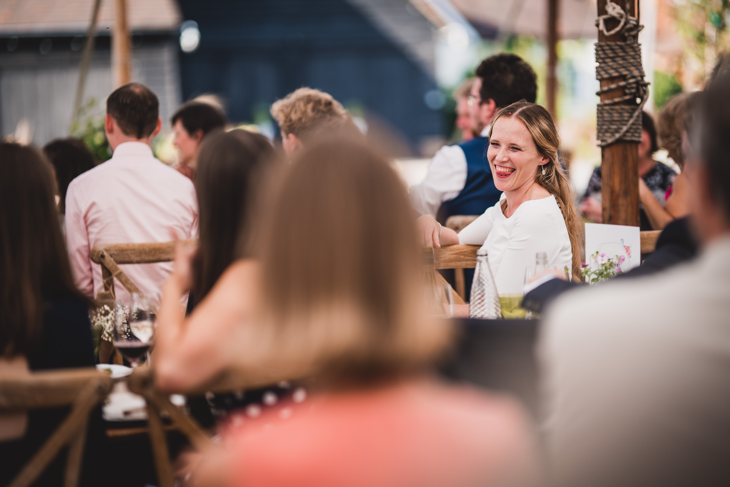 A wedding photographer captures a joyful bride and groom sharing a laughter-filled moment at their reception.