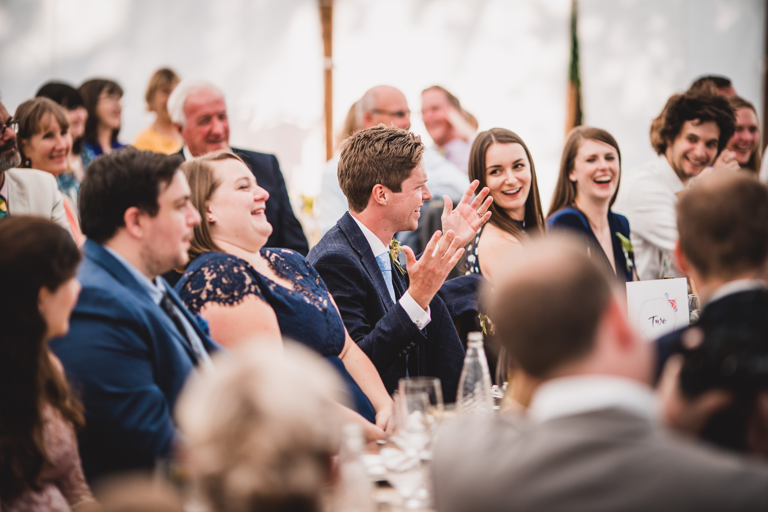 A group of wedding guests enthusiastically clapping in celebration at the bride's reception.
