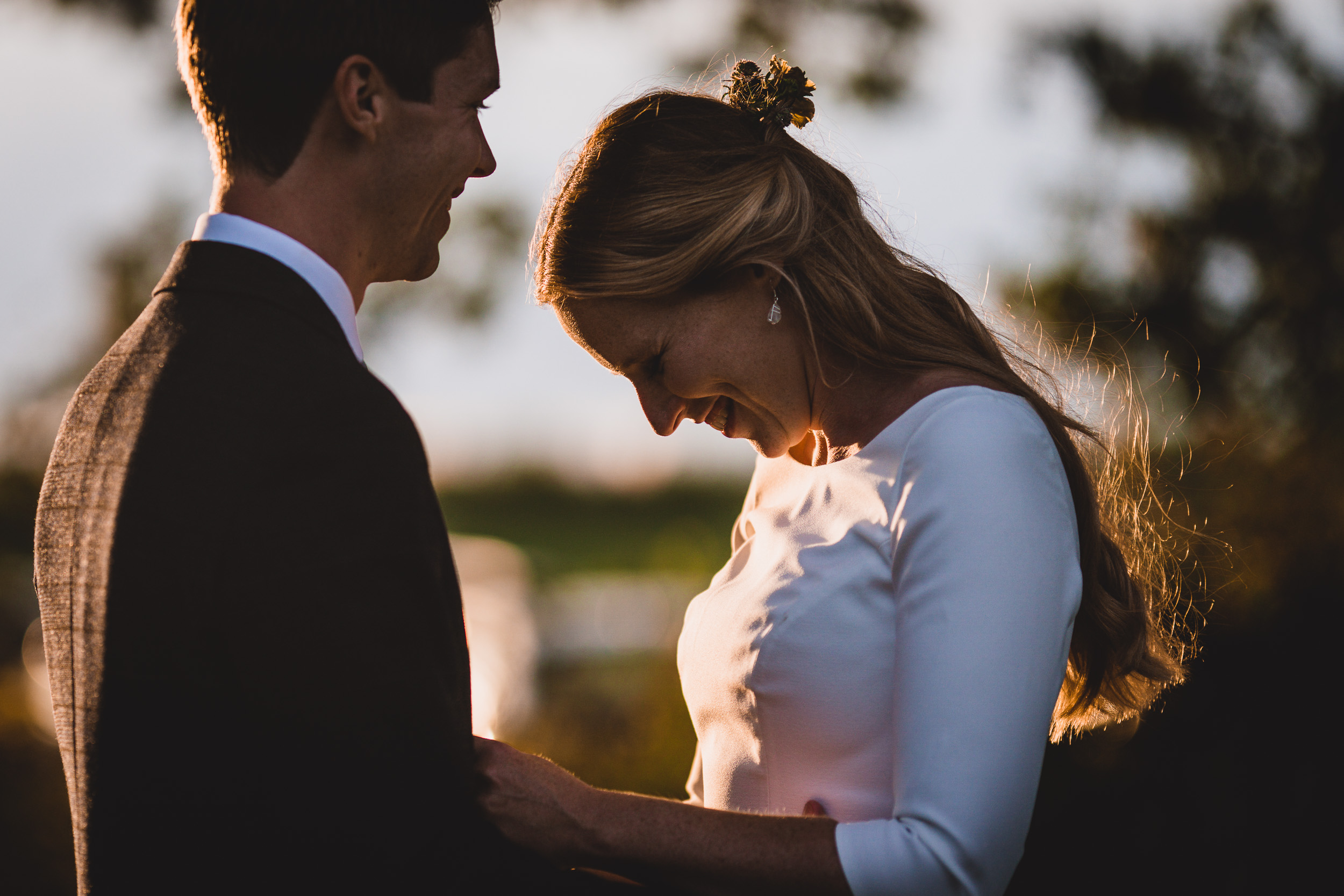 A wedding photo captures the intimate moment of a bride and groom gazing at each other during sunset.