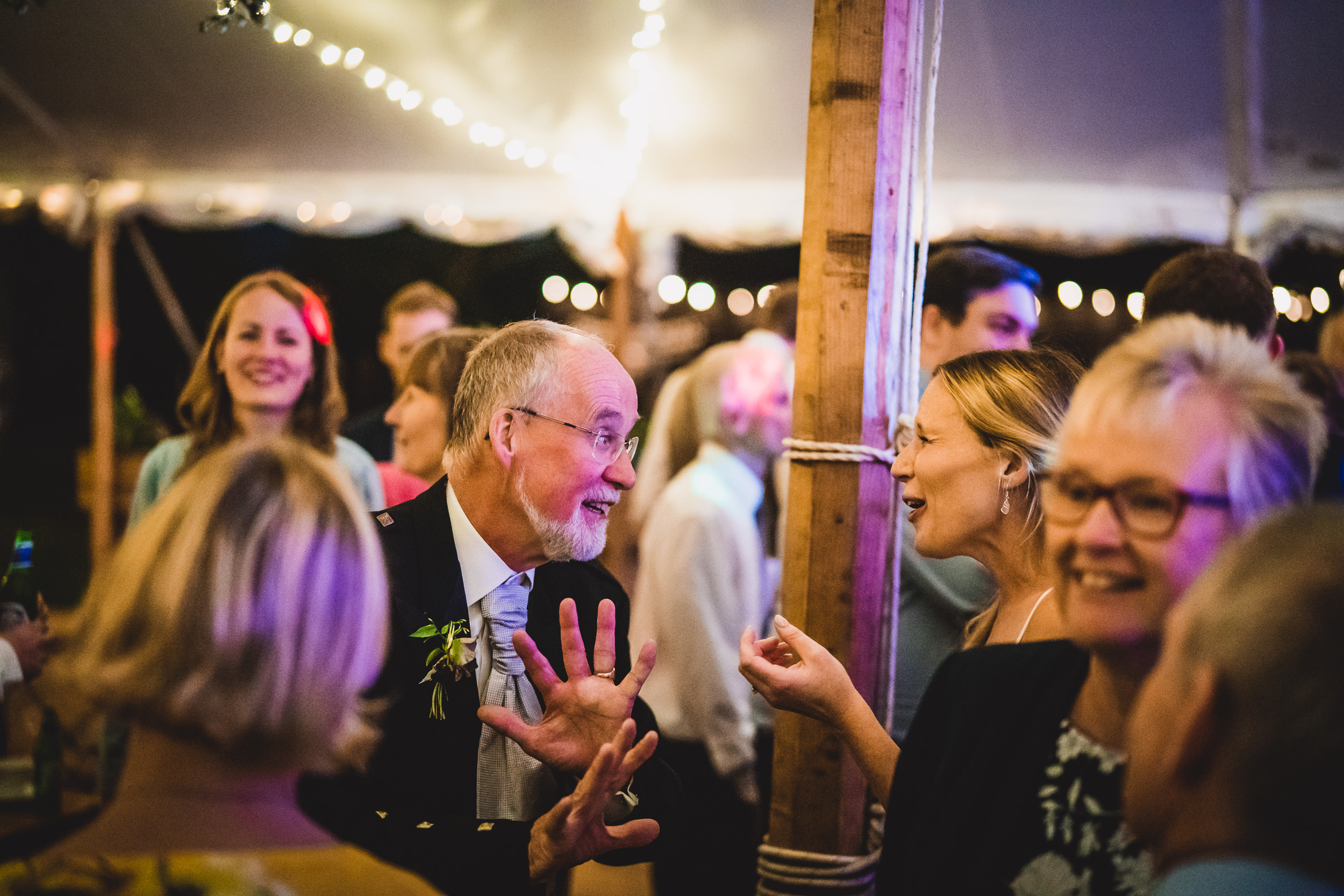 A group of people dancing in a tent at a wedding reception, captured in a joyful wedding photo.