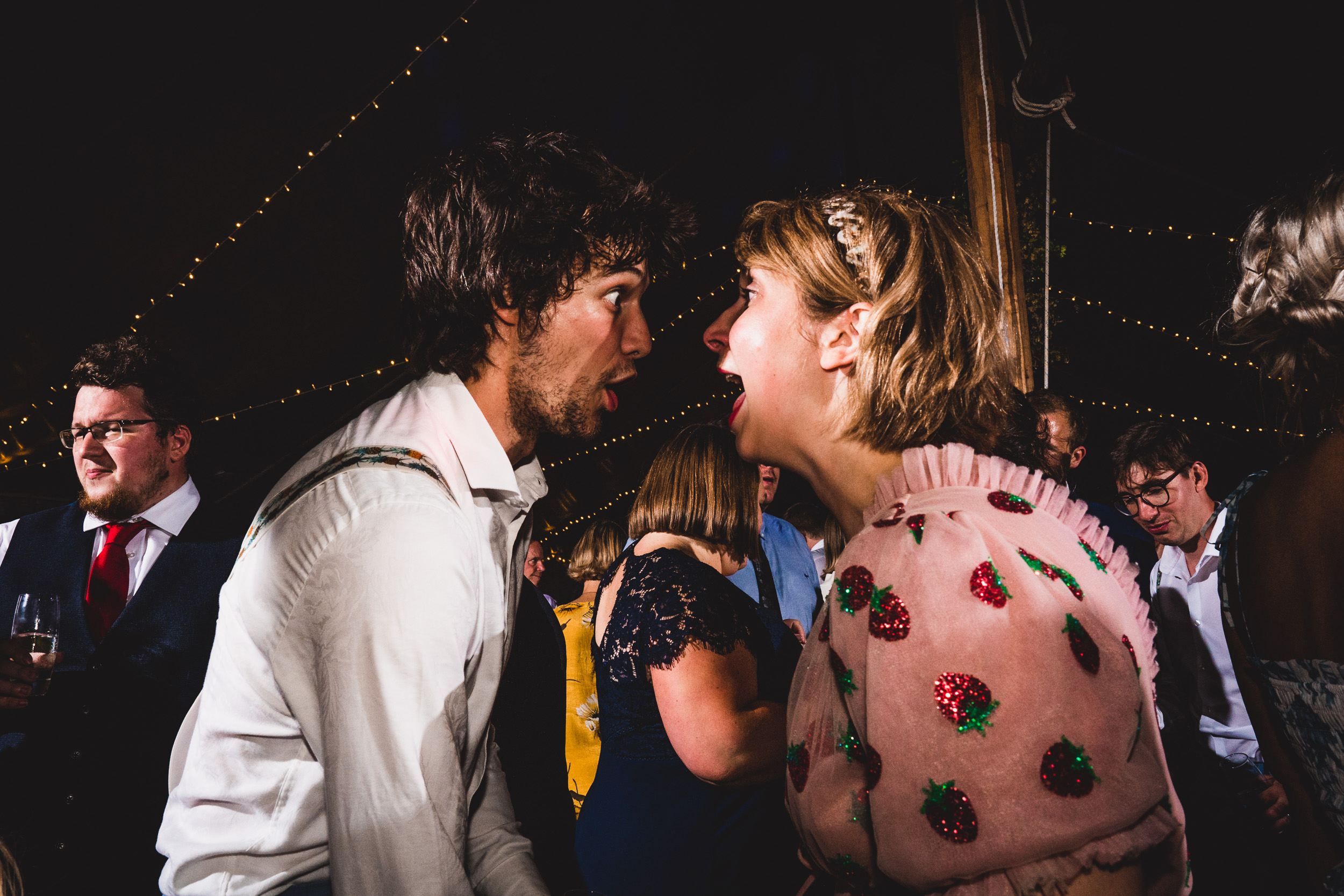 A wedding photographer captures the bride and a man laughing together during the wedding photoshoot.