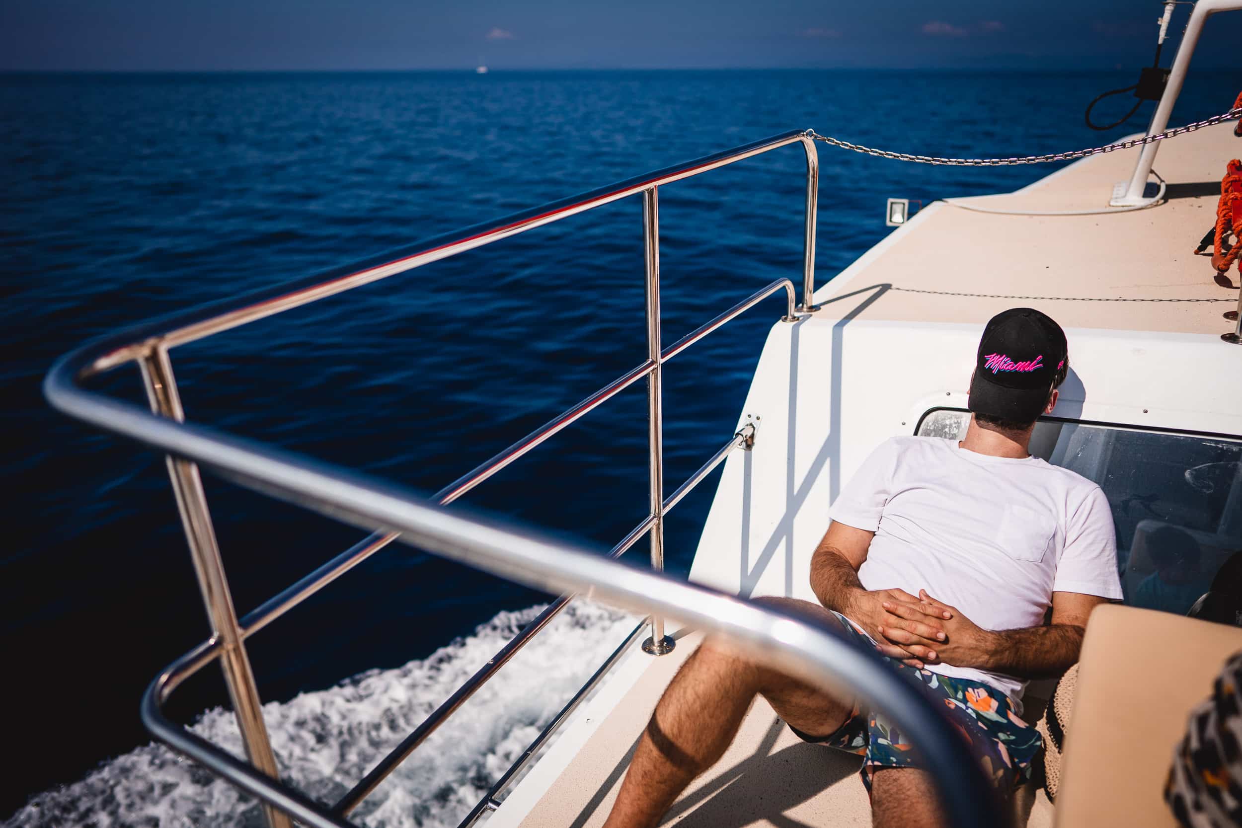 A bride and groom pose for their wedding photographer on the deck of a boat.