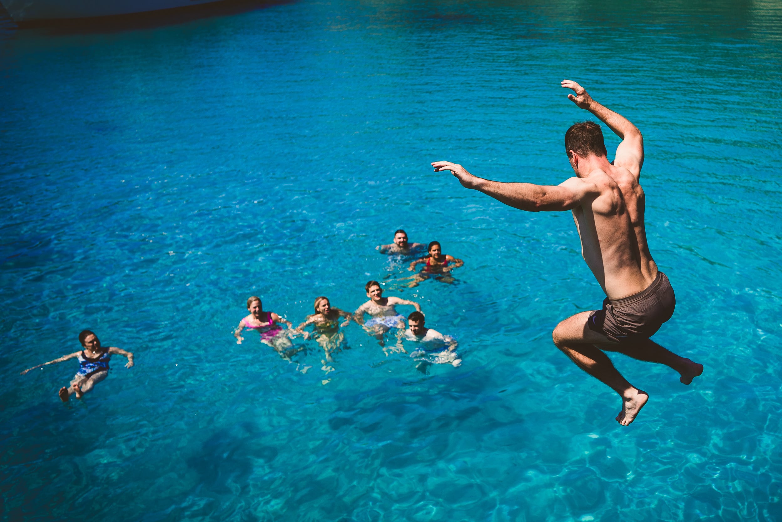 A groom jumping into the water for a unique wedding photo.