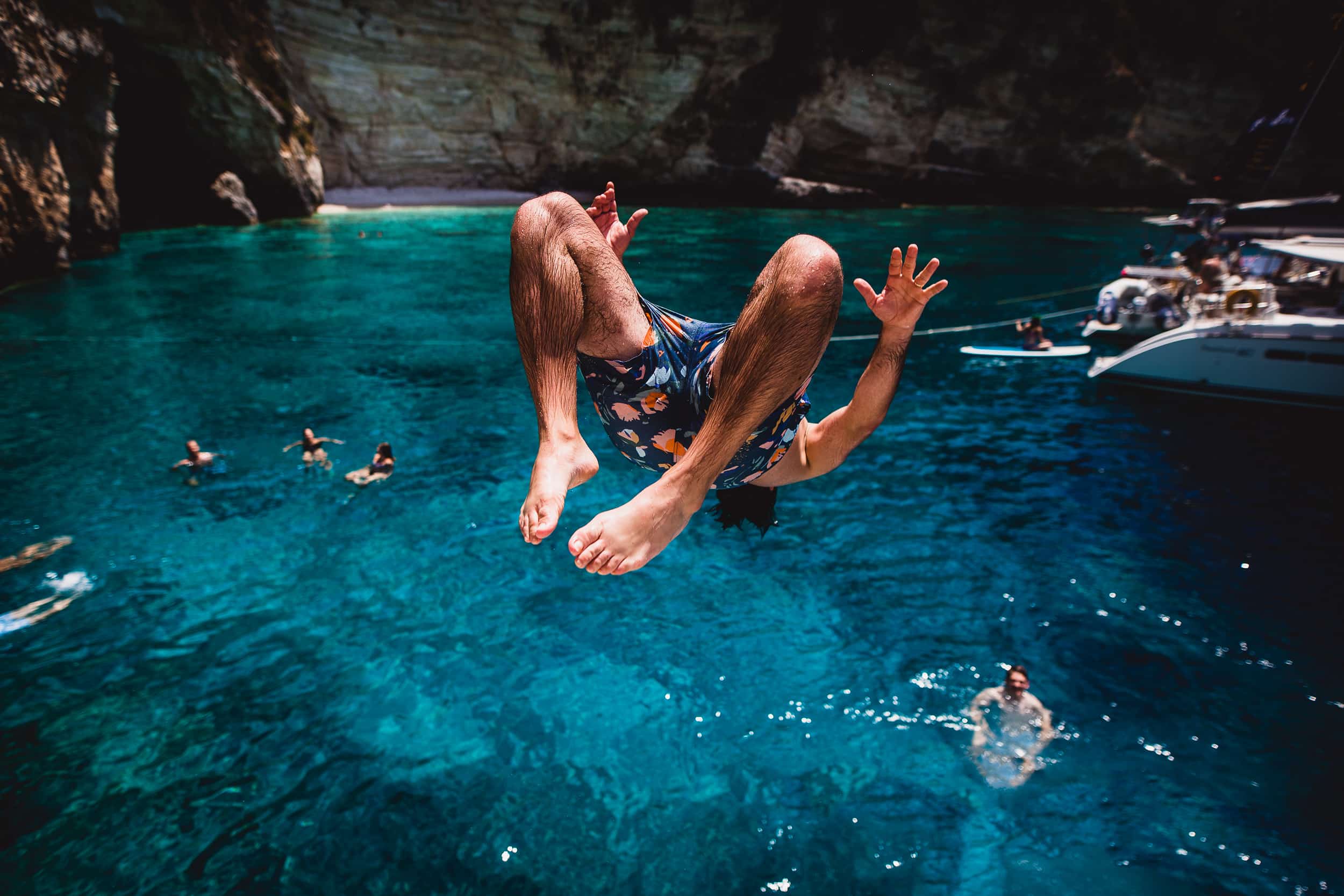 A groom jumping into the water during his wedding photoshoot.