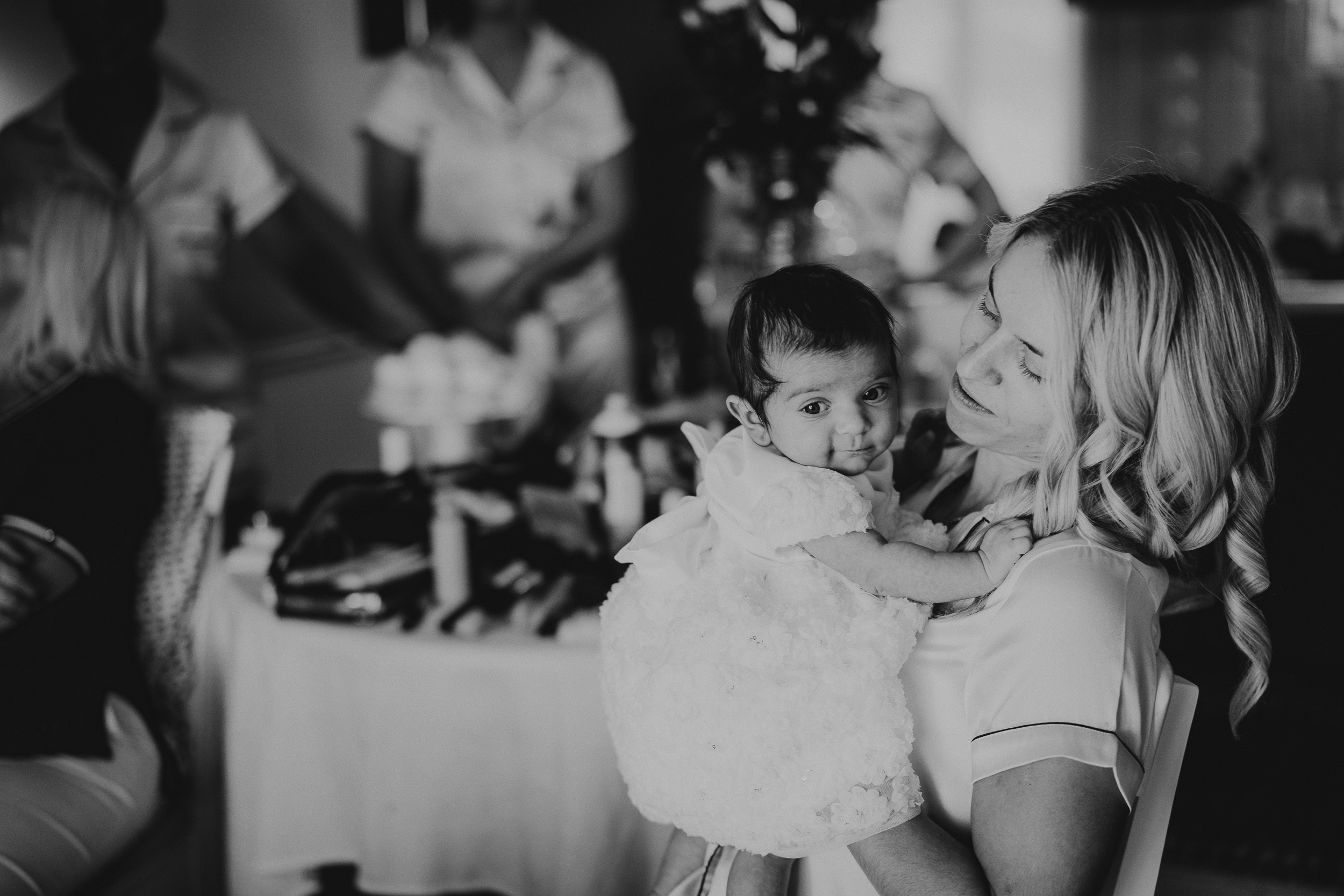 A bride holding a baby in front of the wedding party.