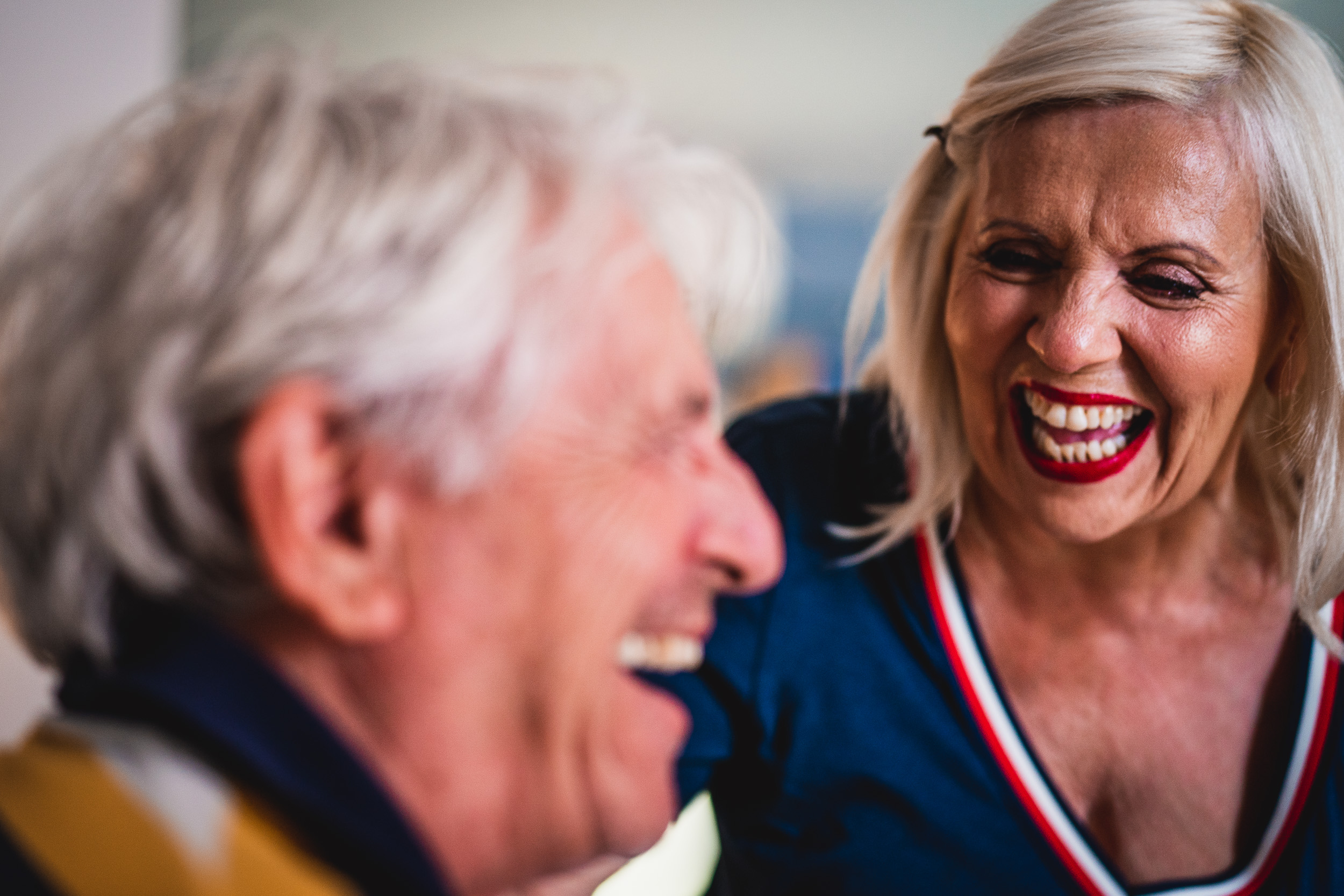 An older woman laughing with the groom at a wedding.