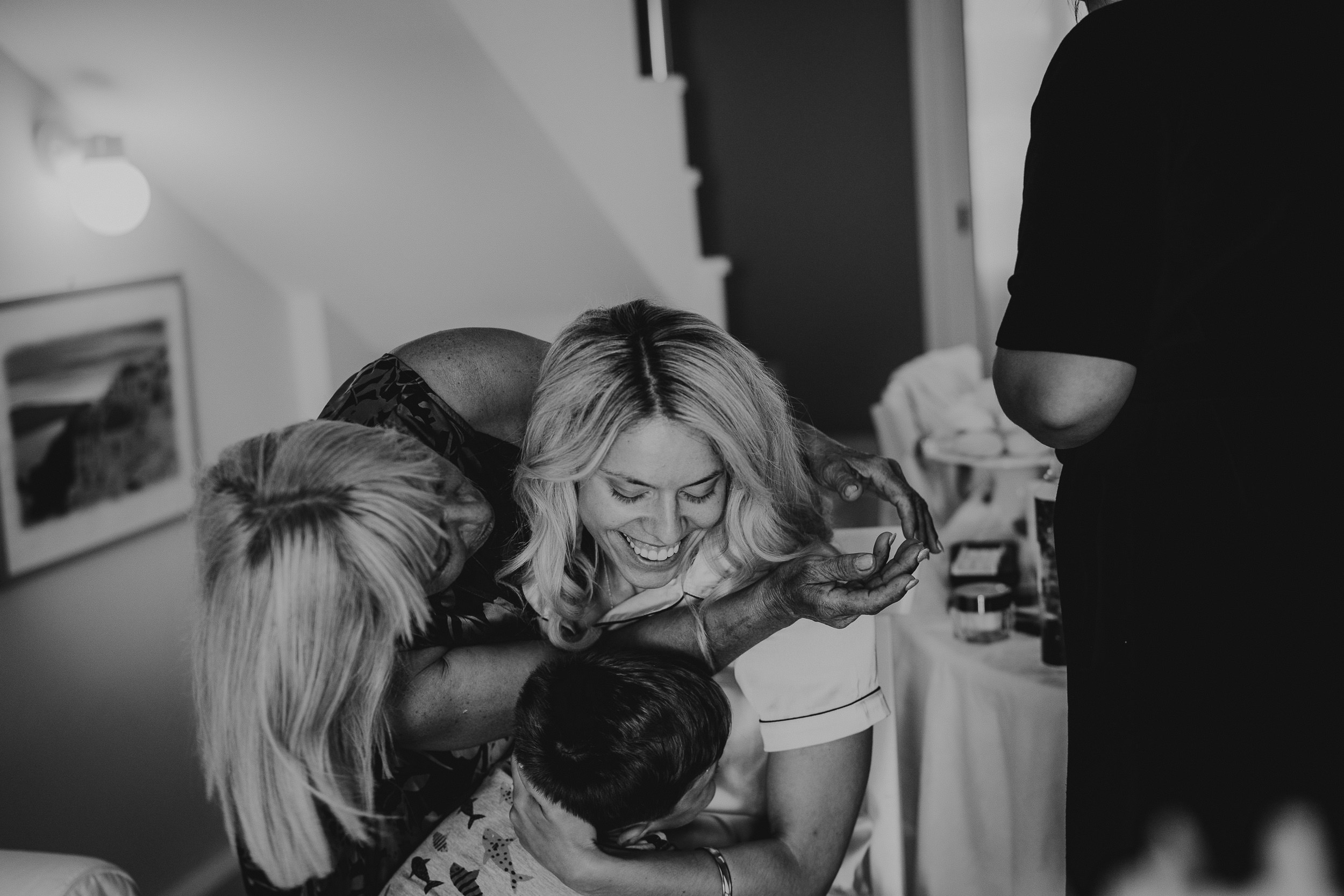 A black and white photo capturing the tender embrace of two women at a wedding ceremony.