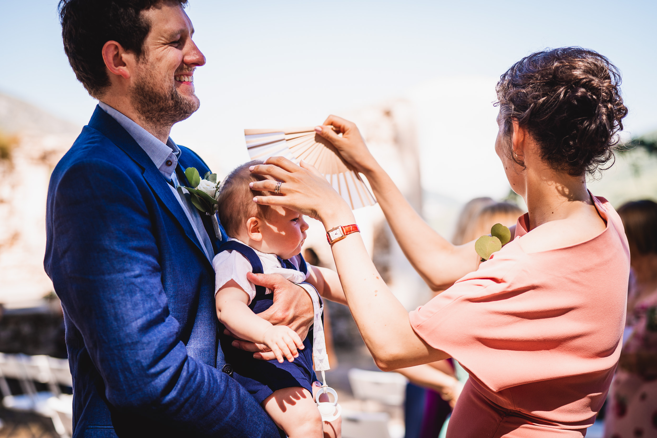 A wedding photographer captures a woman holding a baby during a ceremony.
