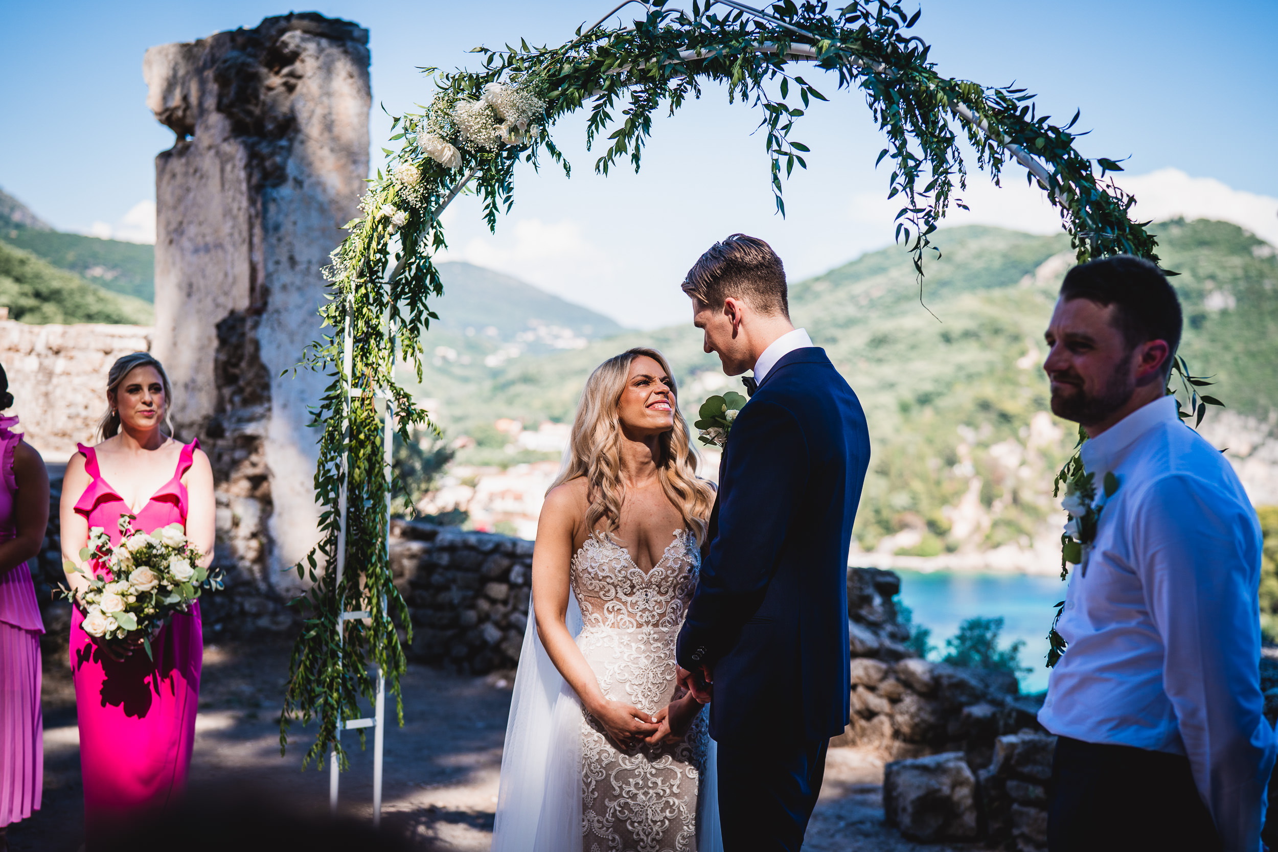 A wedding photographer captures a bride and groom under an arch during their wedding ceremony in Croatia.